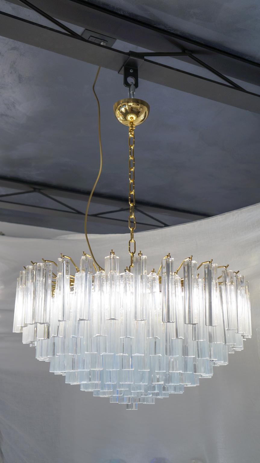 Murano blown glass chandelier with 169 elements in antique crystal, gold finish structure and 9 lights E26 / E27. The elements of this typical chandelier are called Triedri, for its triangular shape. The assistants take a small quantity of glass