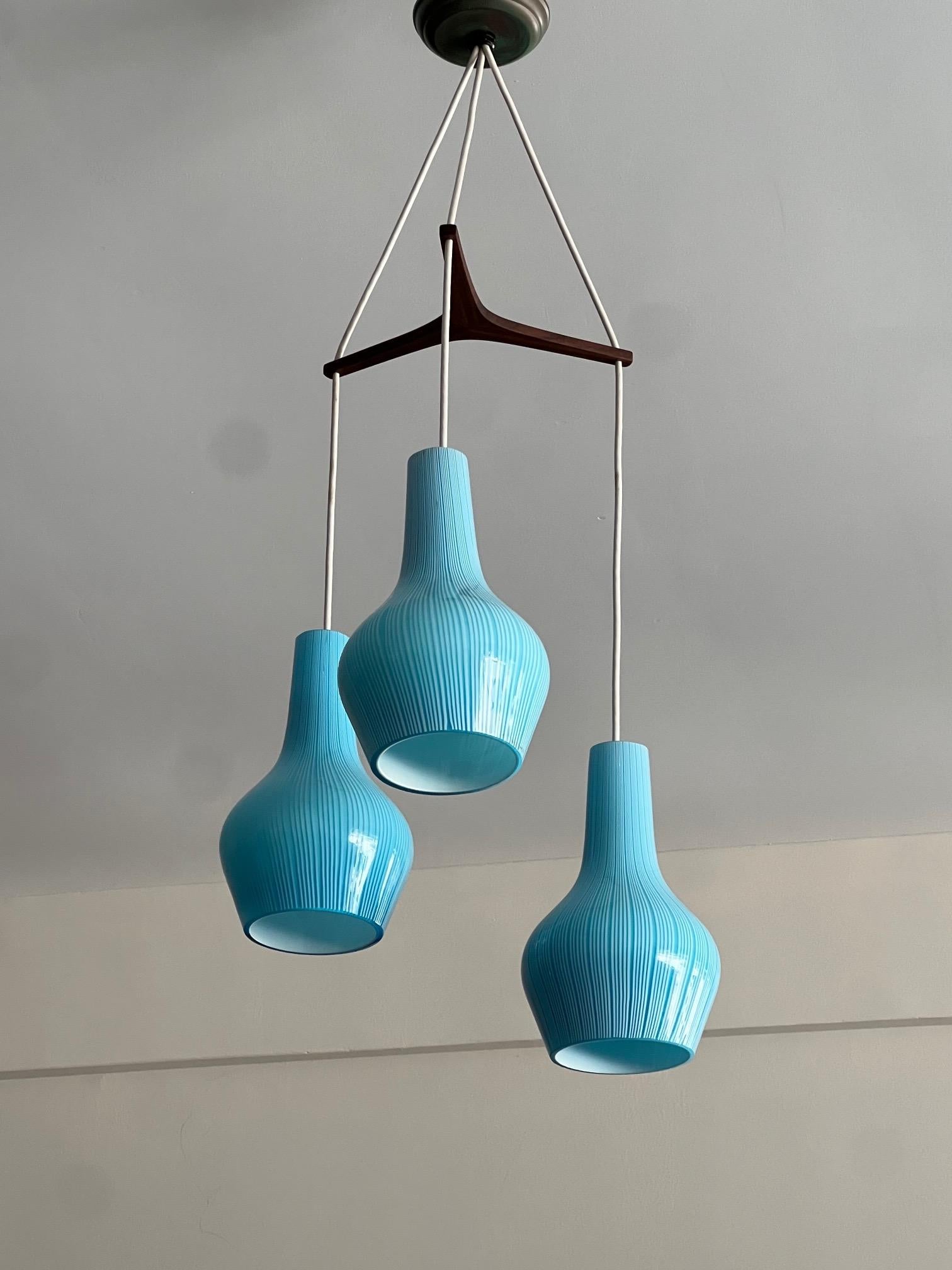A beautiful blue, cased glass, onion shaped shades-M.Vignelli for Venini, Italy, 1950's, chandelier. Three shades, stripes, slight differences, teak tripod shaped mount, canopy replaced. The height of the pendants can be adjusted depending on need,
