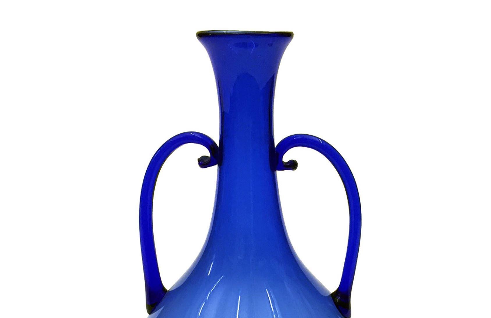 Venini blue vase with two blue thin handles.

Property from esteemed interior designer Juan Montoya. Juan Montoya is one of the most acclaimed and prolific interior designers in the world today. Juan Montoya was born and spent his early years in