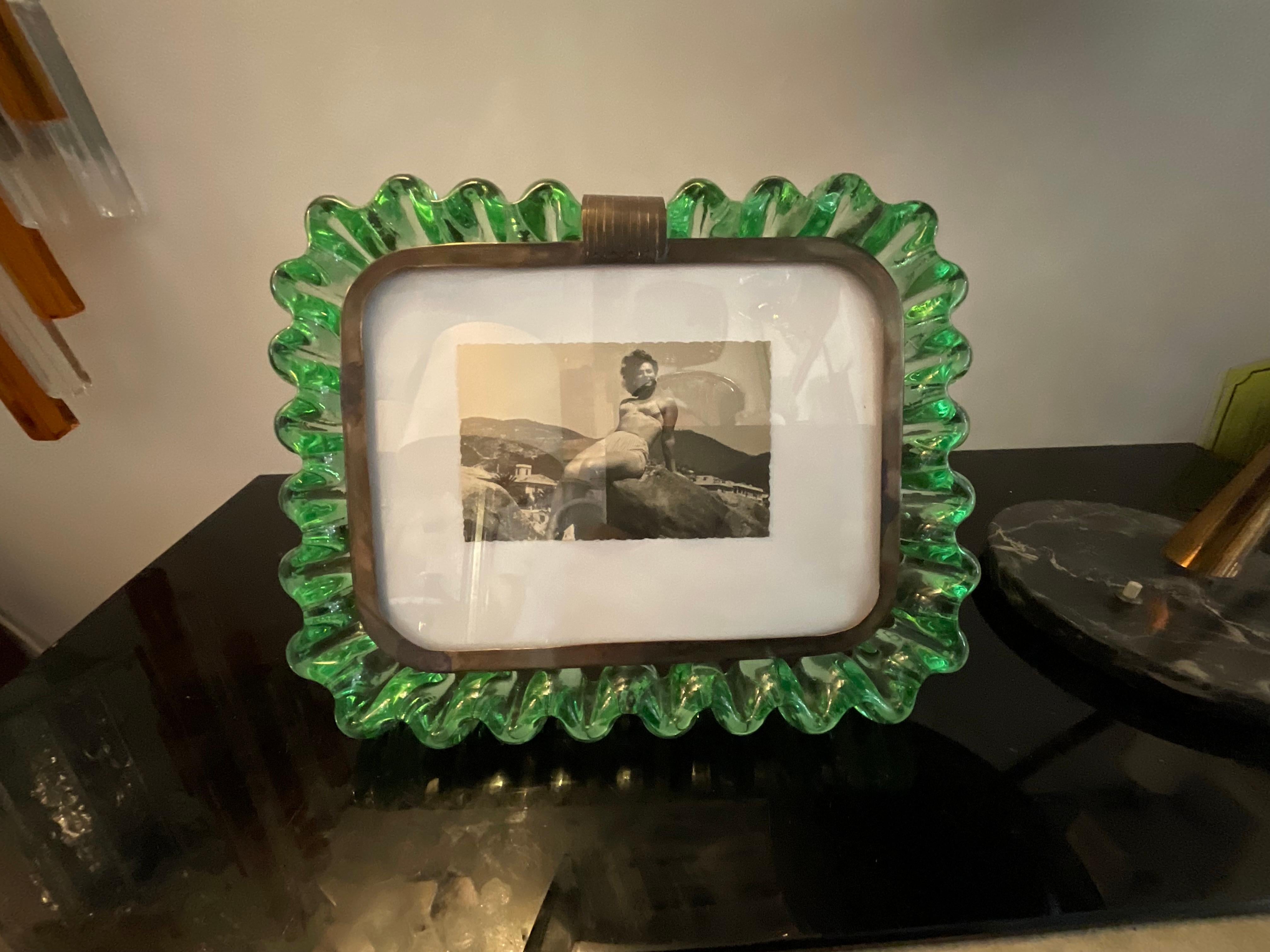 Beautiful and rare frame due to wavy shape of the glass and green color, as well as horizontal because most of these portrait frames are vertical and the glass transparent .
An original piece from 1940, designed by Carlo Scarpa and executed in the