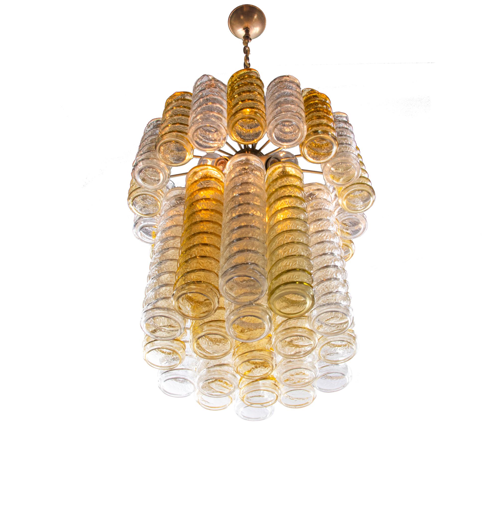 Élégant lustre à tourbillons conçu par Paolo Venini avec trente-sept grands verres de Murano torsadés, ambrés et transparents, suspendus en deux étages autour d'une armature en laiton chromé, qui grâce à un éclairage puissant offre un beau jeu de