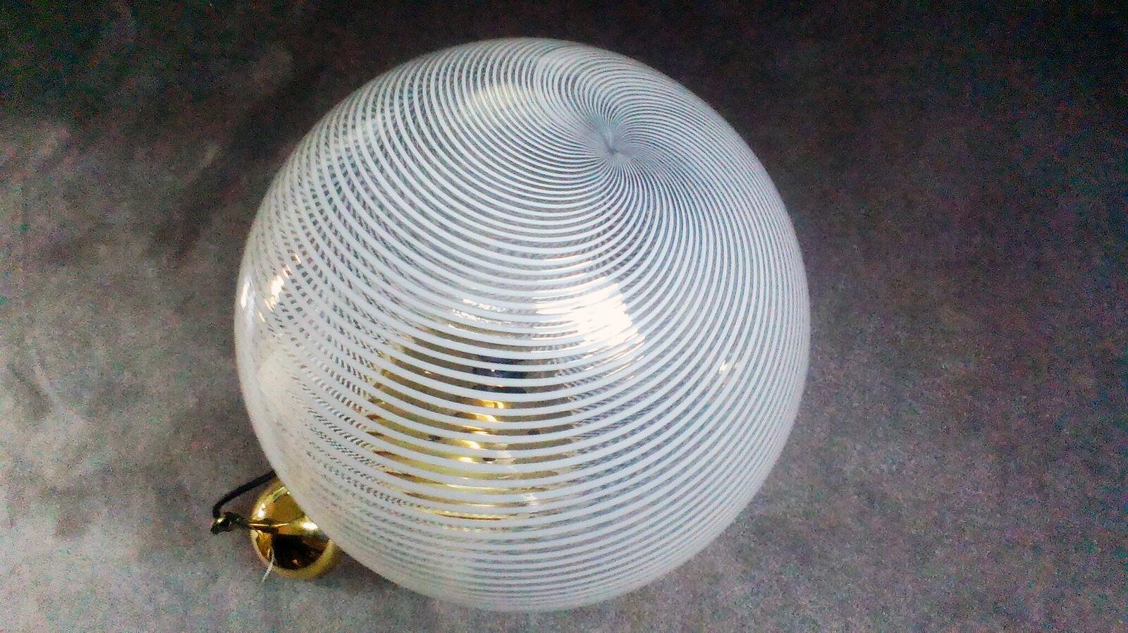 An elegant spherical ceiling lamp realized in hand blown glass with filigree technique and particular brass details, manufactured in Italy by Venini in 1950s.
This spherical pendant facilitates a diffuse light illumination and its clean line makes