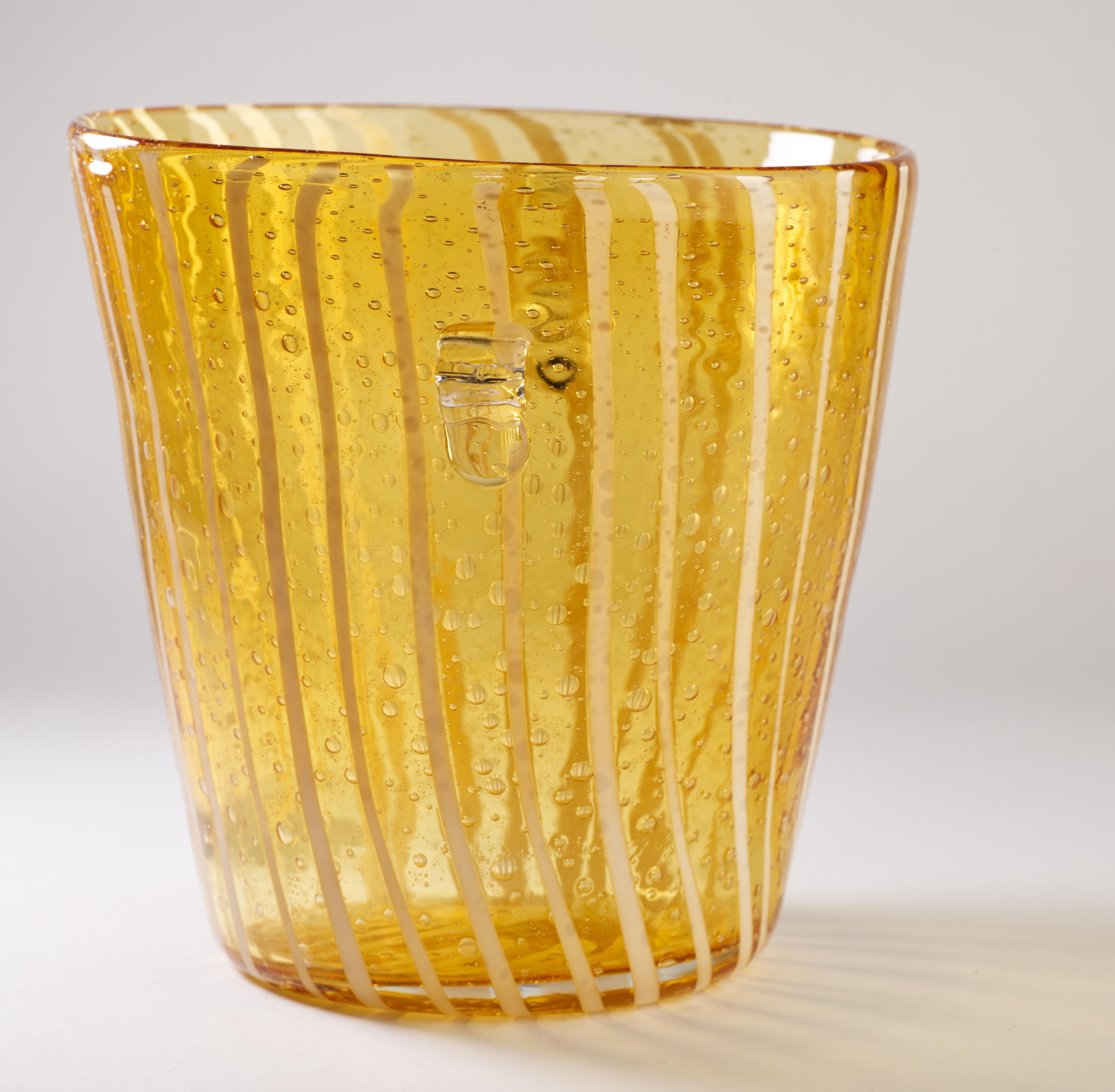  La cubitera vintage modernista tiene una decoración geométrica abstracta de cristal blanco fundido sobre cristal transparente de color ámbar con efecto de burbujas controladas. La pieza tiene dos pequeñas asas redondeadas realizadas en cristal