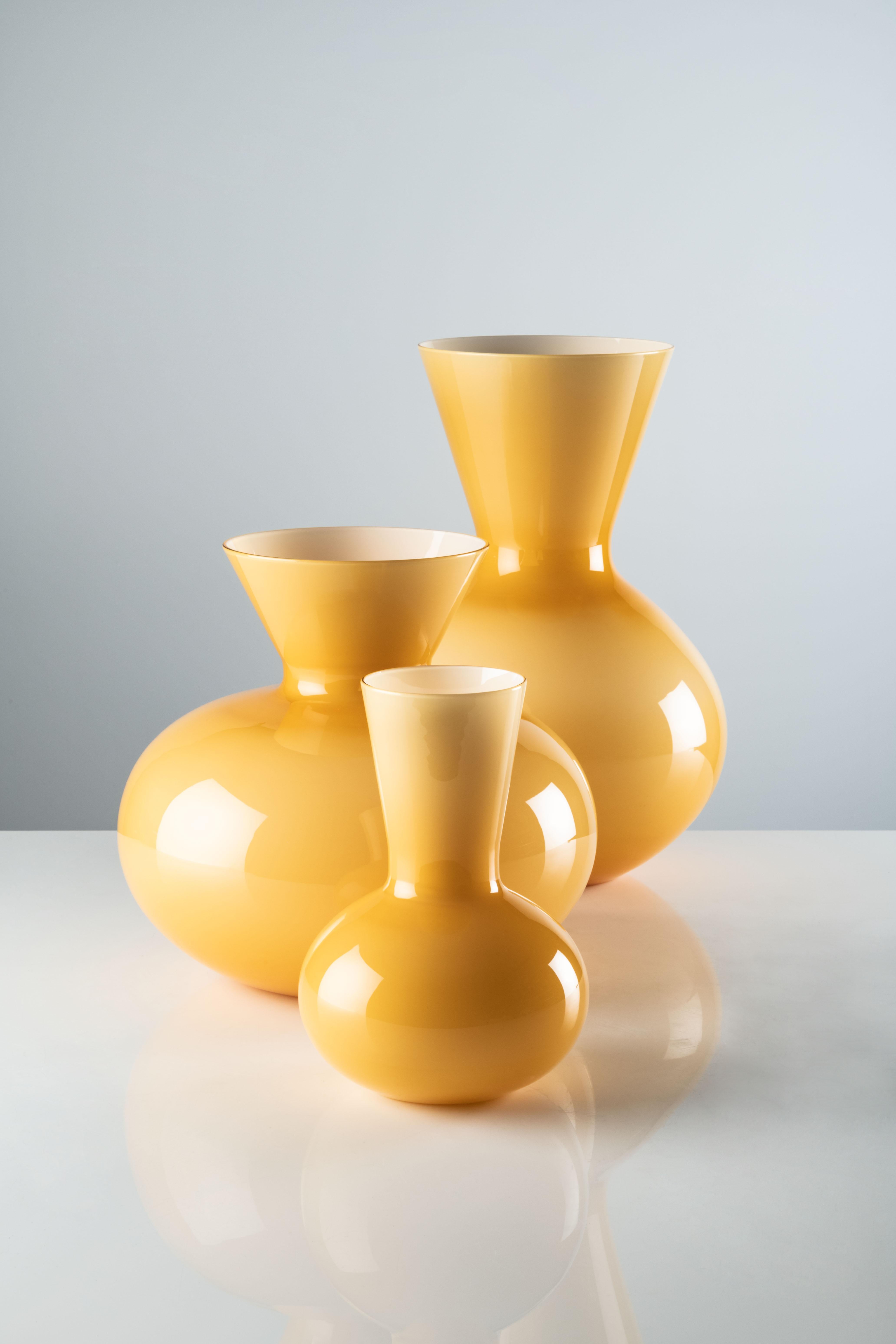 Idria small vase in Amber Murano glass by Venini. The Ancient Greek water vessel sheds its skin, as terracotta gives way to glass, thanks to Venini. Its design speaks of bygone days and rhythms, bringing them back to life: timeless beauty that