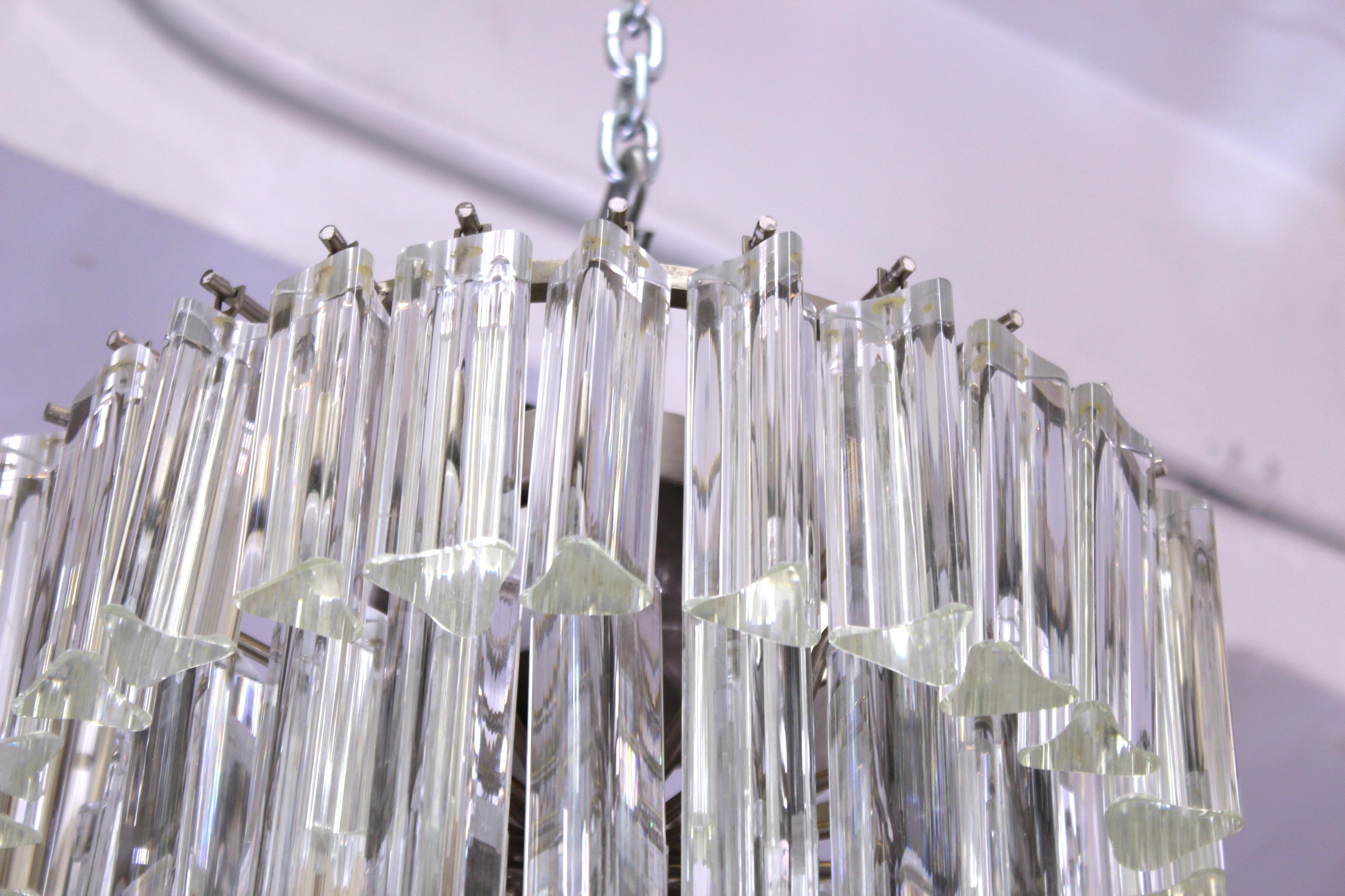 Italian modern glass prism chandelier by Venini, made of multiple tiers of triedri glass prisms. The piece is in great vintage condition with age-appropriate wear.
Also available as a pair.