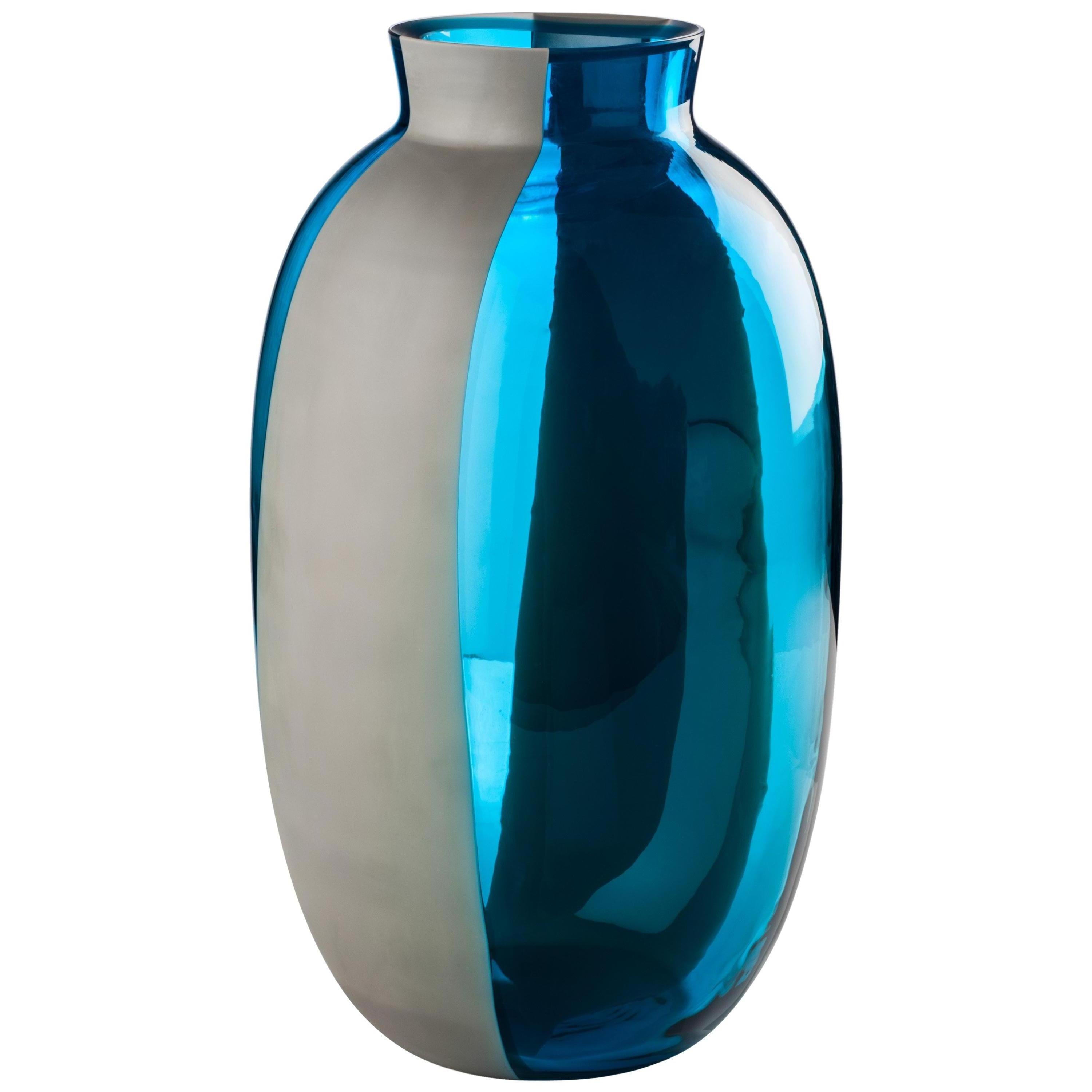 Koori vases, designed by Emmanuel Babled and manufactured by Venini, feature a concrete band melted with the glass. Numbered edition. Indoor use only. Color: Transparent Aquamarine / Concrete Band Satin finish.

Dimensions: Ø 22 cm, H 38 cm.