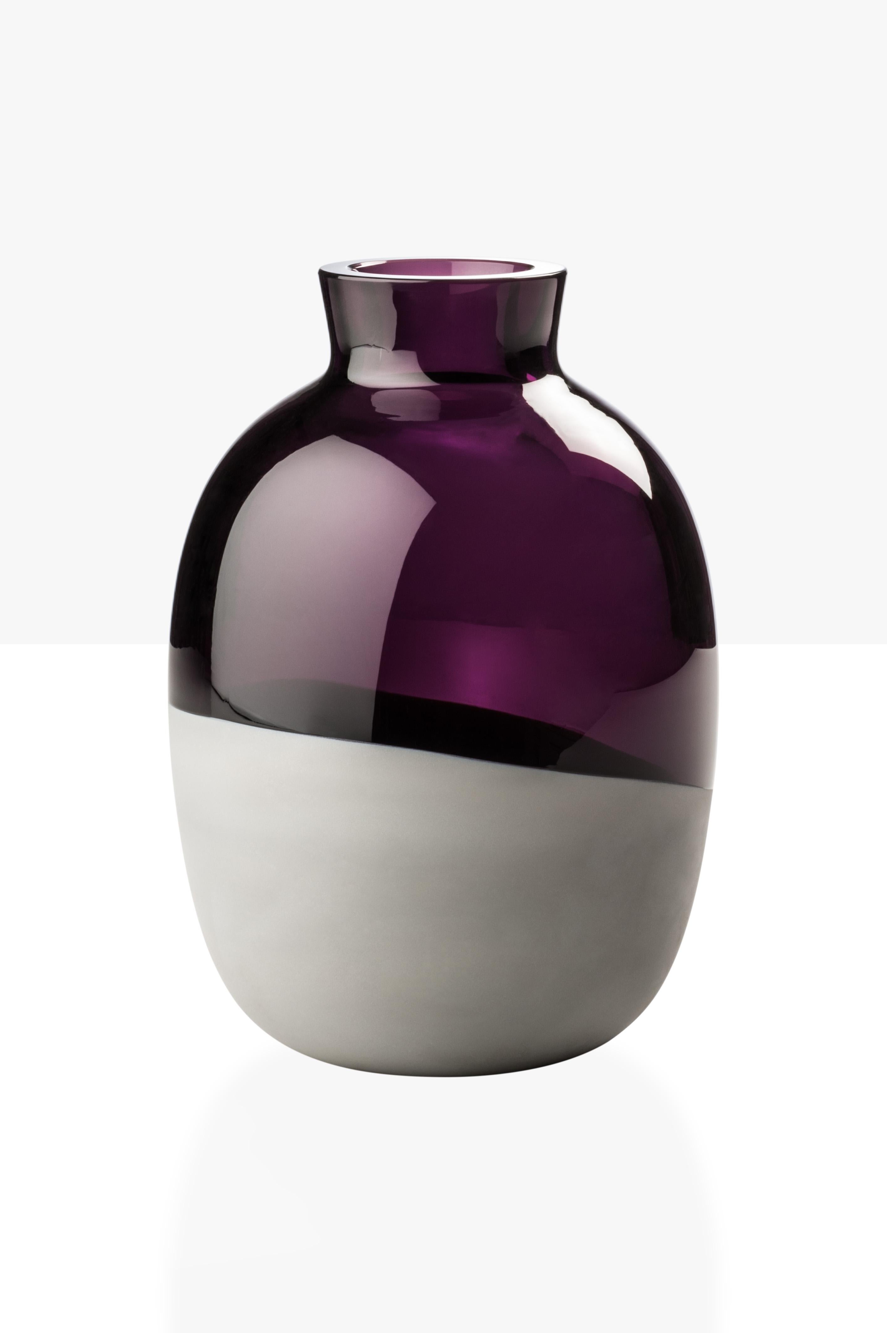 Koori vases, designed by Emmanuel Babled and manufactured by Venini, feature a concrete band melted with the glass. Numbered edition. Indoor use only. Color: Transparent violet/ concrete band satin finish.

Dimensions: Ø 15.6 cm, H 22 cm.
