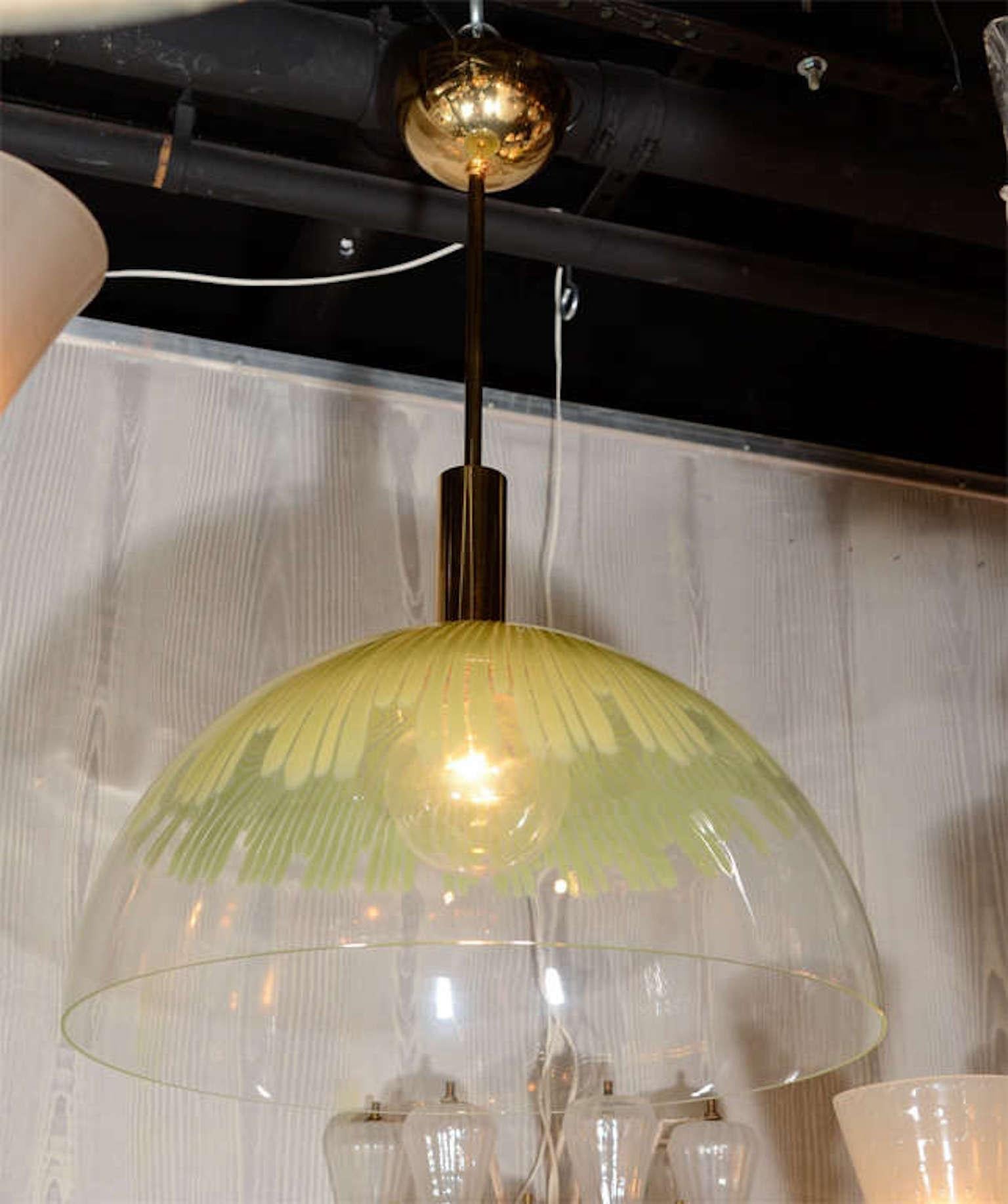 A documented pendant light by designed Ludovico Diaz de Santillana. Santillana was the director and a designer for the famed glass house Venini from 1959-1985. Dome shade is hand blown clear glass with green stripes suspended from a gold plate on