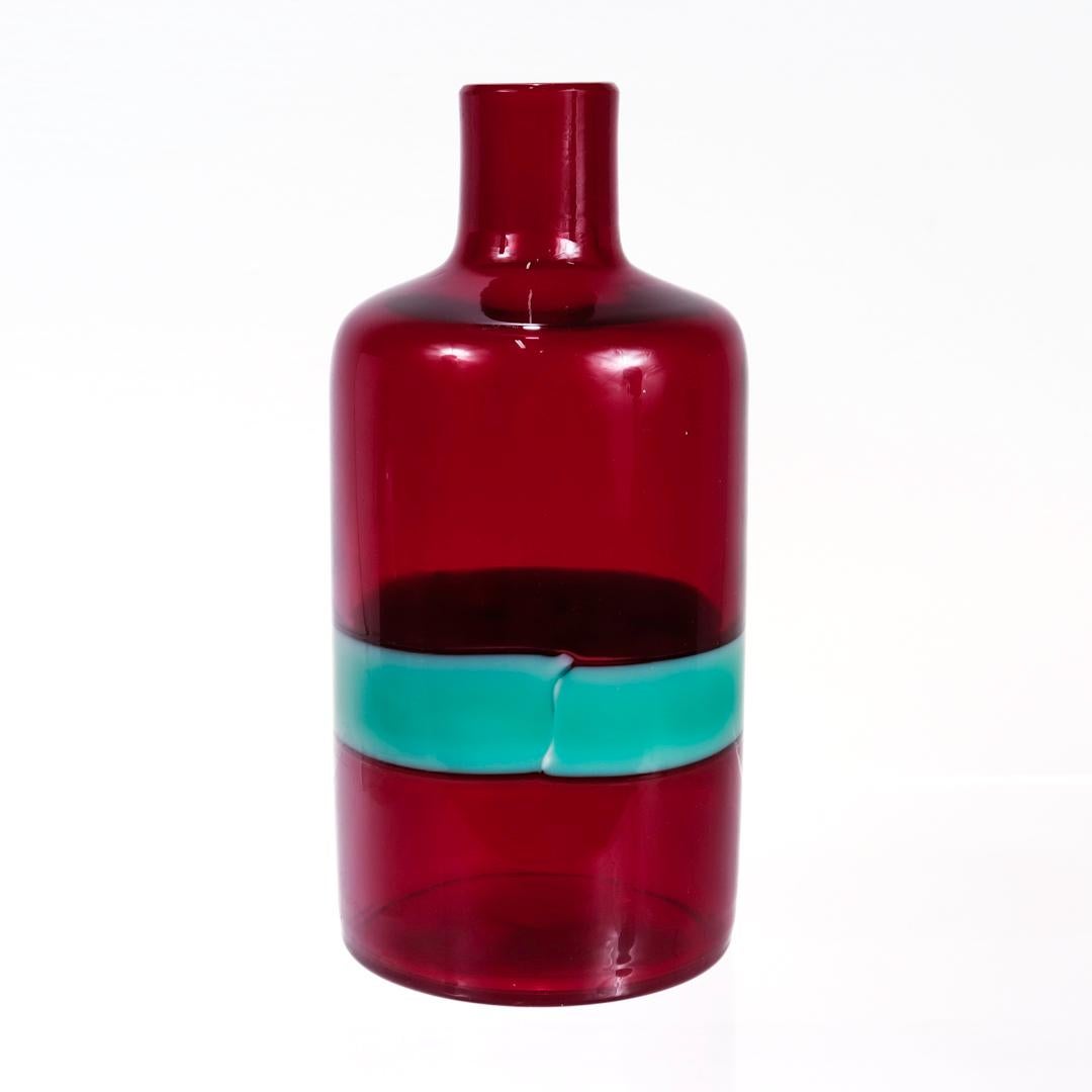 Eine schöne Flasche aus italienischem Kunstglas aus der Mitte des Jahrhunderts.

Eine so genannte 'a fasce orizzontali' Flasche mit einem breiten türkisfarbenen Band in einem klaren roten Körper.

Von Venini.

Entworfen von Fulvio Bianconi.

Auf dem