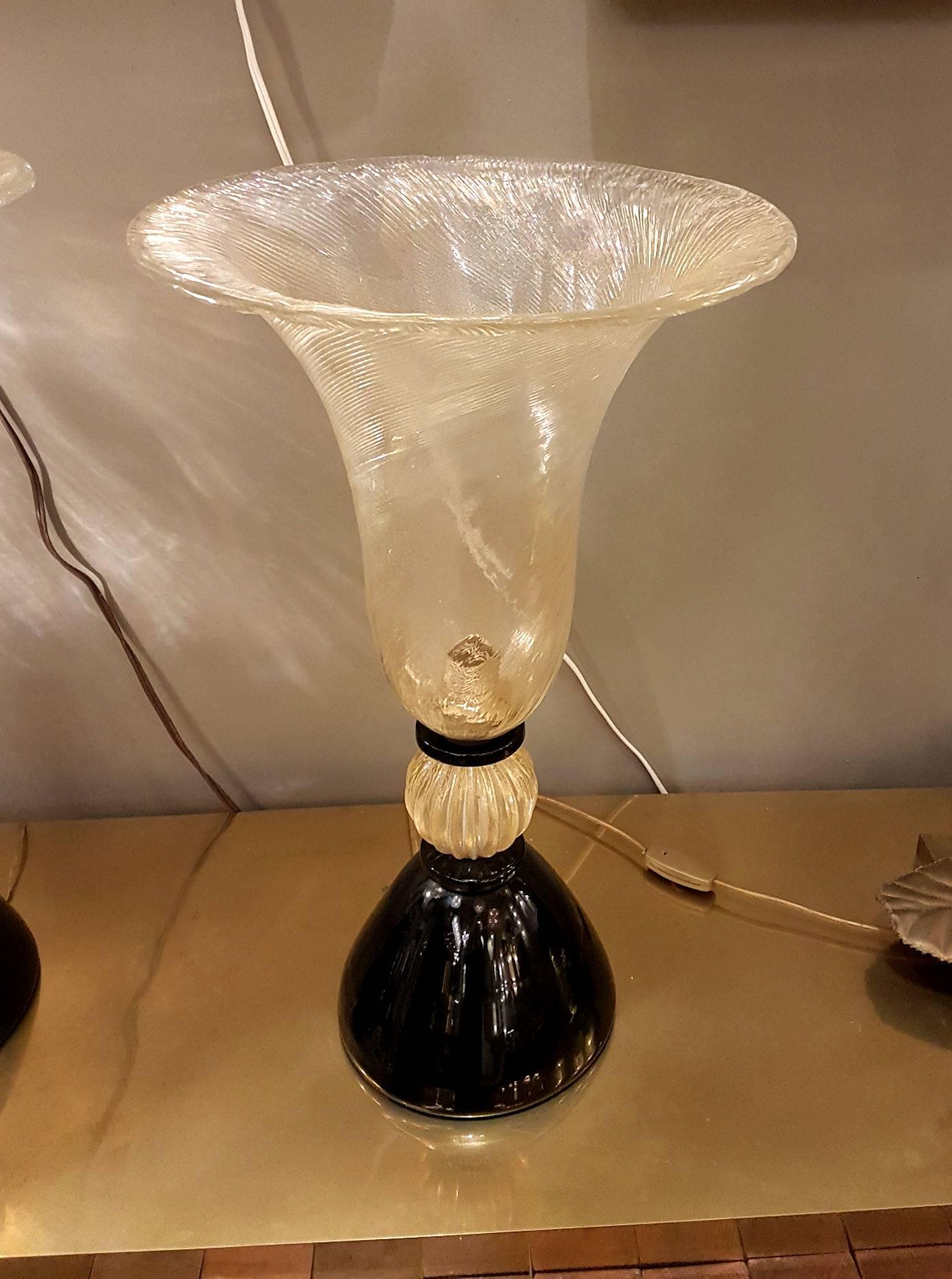 Large pair of Mid-Century Modern Murano glass urn shaped lamps, Venini style and quality.
Made of a black opaque Murano glass base, and a large clear with gold inclusions top vase, containing the light, and decorated with the Rigadin Murano glass