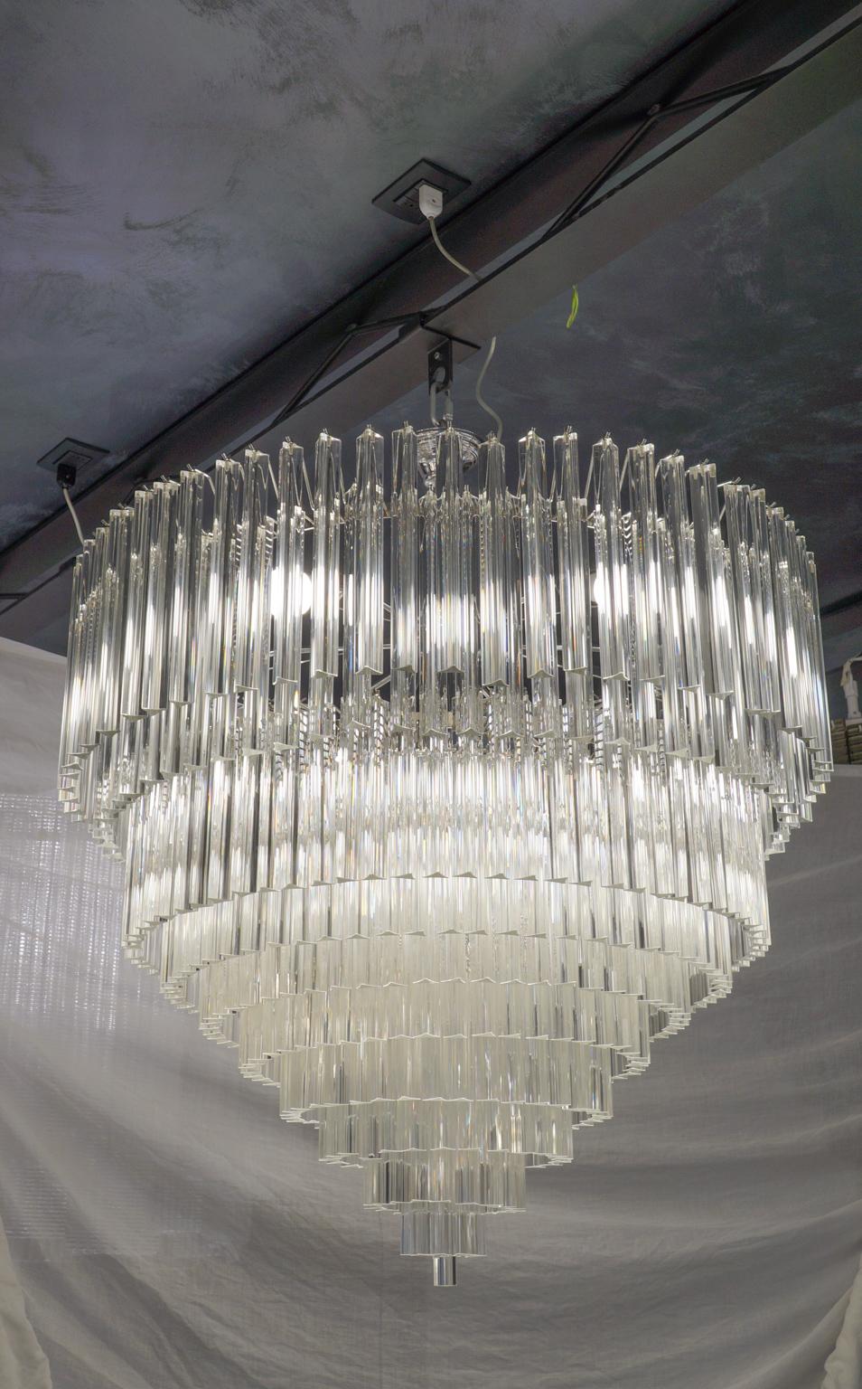 Murano glass chandelier with 457 elements in crystal, nickel finish structure and 12 E26 / E27 bulbs. The elements of this typical chandelier are called Triedri, for its triangular shape. The assistants take a small quantity of glass from the oven.