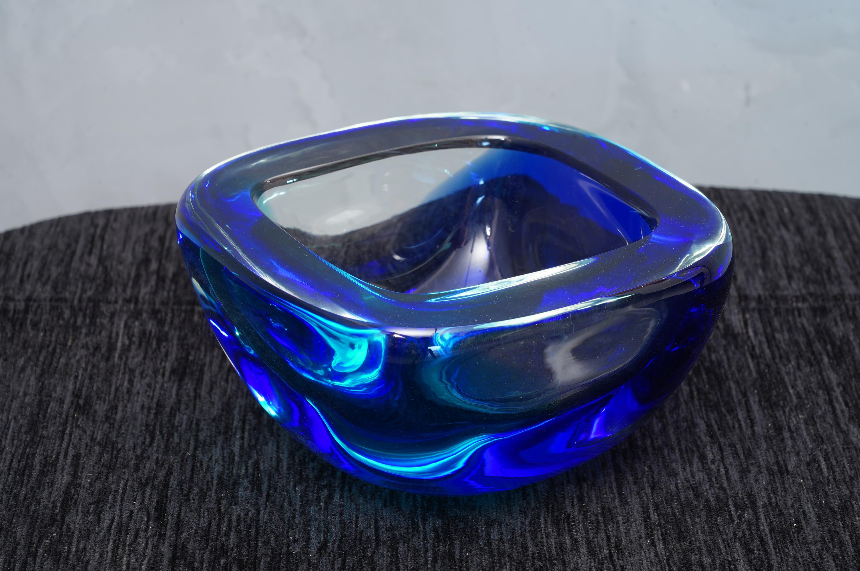Ashtray formed by a particular submerged glass, signed Venini, with a wonderful double blue and azure color.

The ashtray is in Murano glass, square in shape, and with a particular transparent blue and azure color. The signature is placed on the