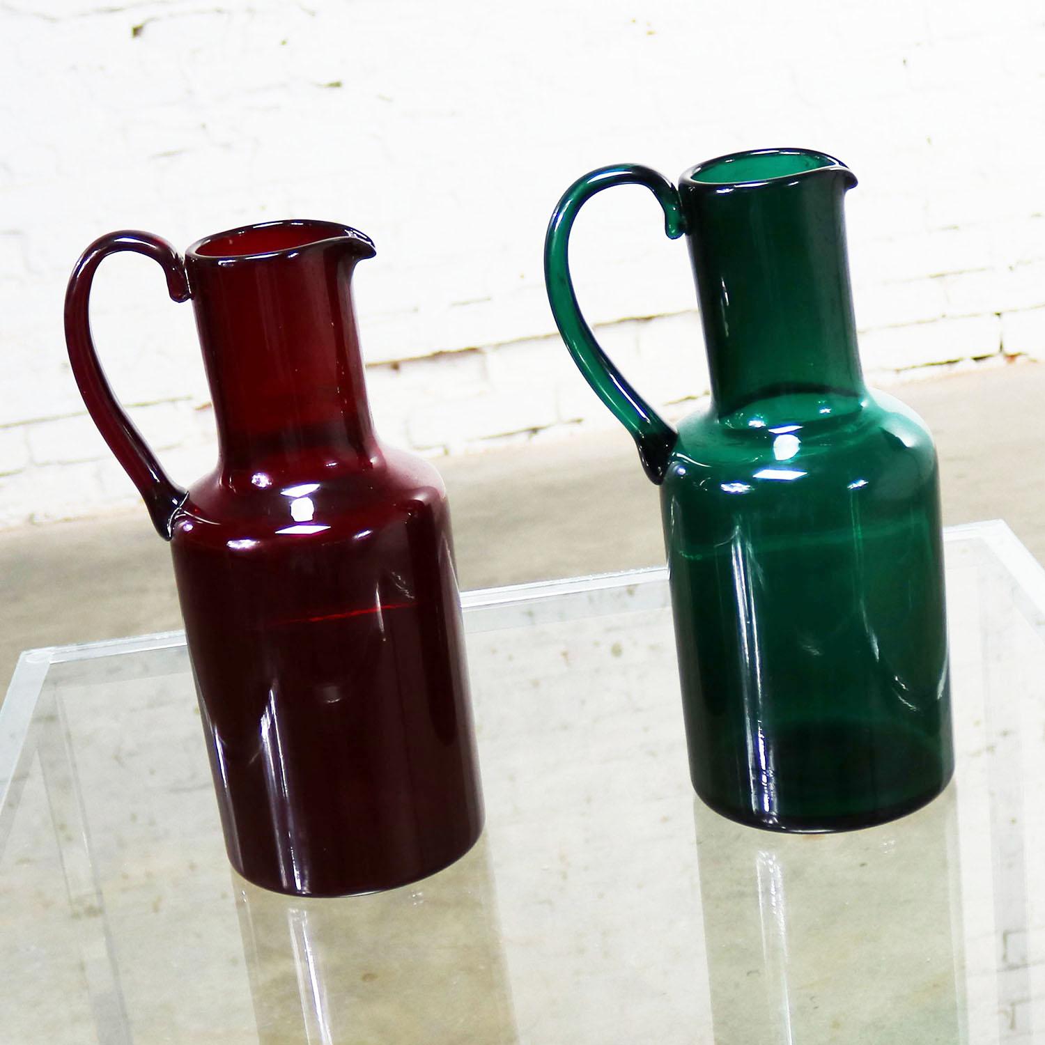 Handsome Murano cocktail pitchers or carafes by Venini. One cranberry red with paper label and acid etched signature and one emerald green with acid etched signature. We are pricing these separately, so you can purchase one or two. They are both in