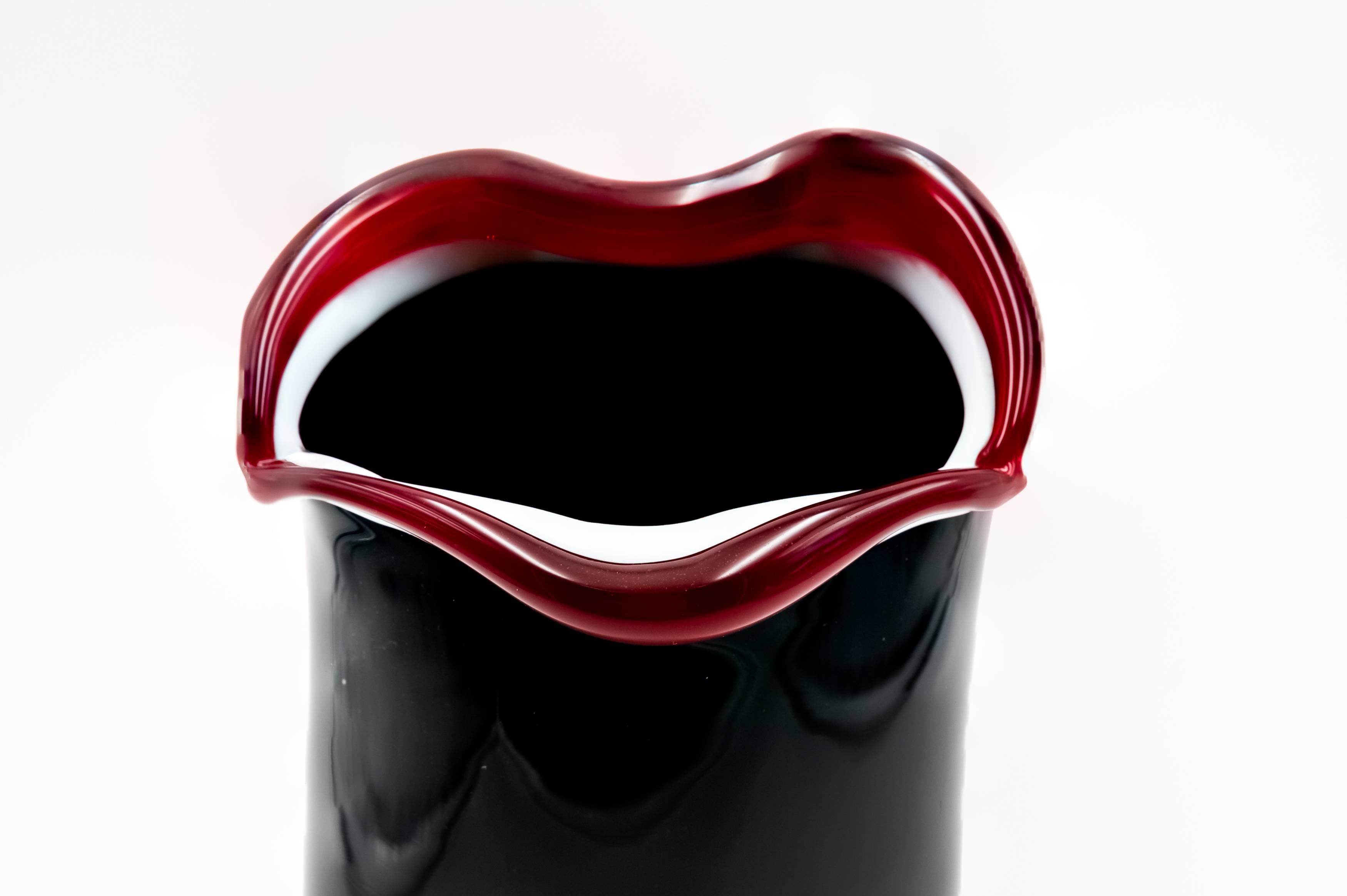 A smile vase designed by Fulvio Bianconi in the 1990s and produced by Venini. 
One of the latest designs by Bianconi.
Very nice black color with applied accents of white and red glass.
Be sure to check our other listings because we have 5 different