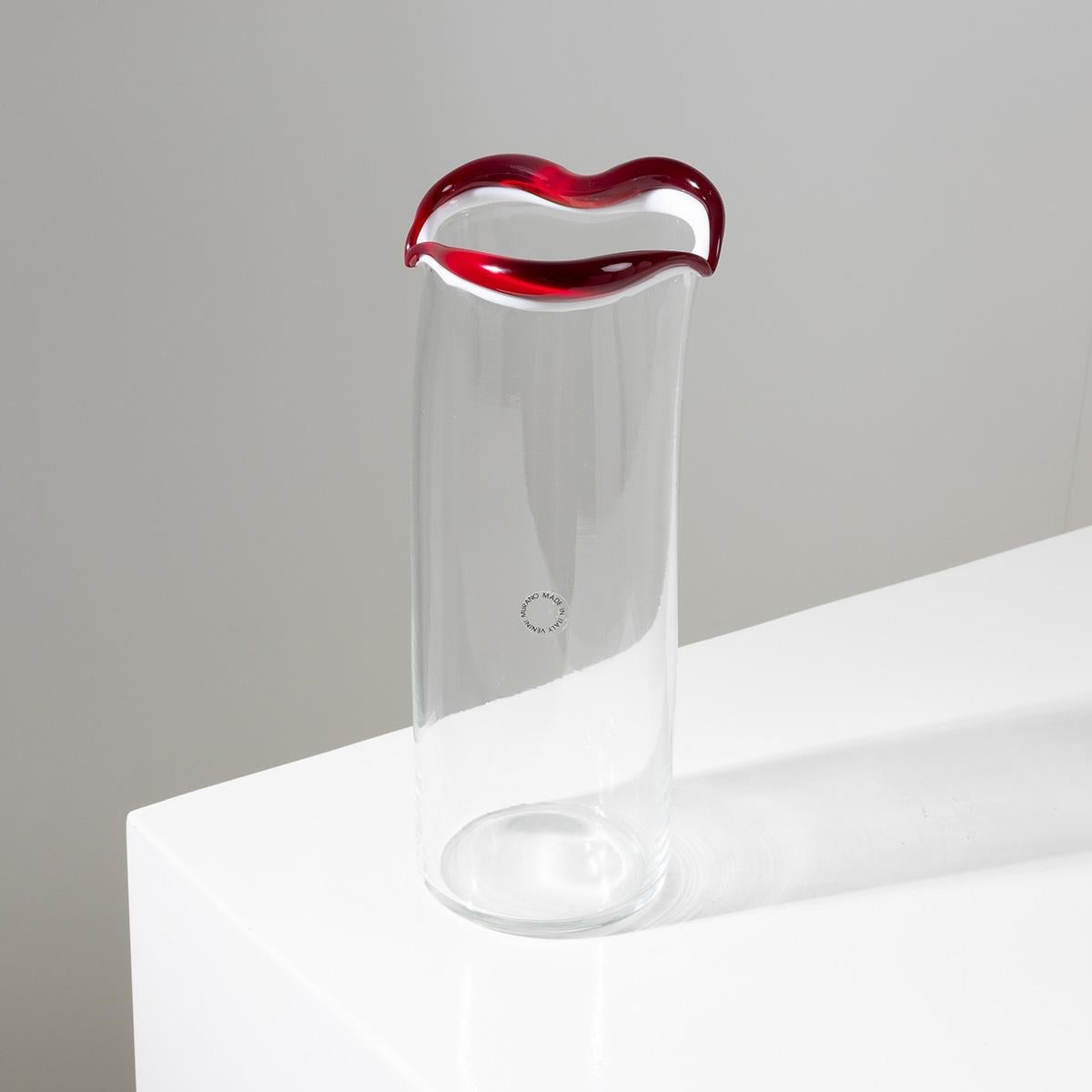 Sorriso is the result of the last series of vases designed by Fulvio Bianconi for Venini at the end of the 80s.
It is a mouth-blown glass vase, on which is applied a milk-white smile with red lips.
The body of the vase is itself made of crystal