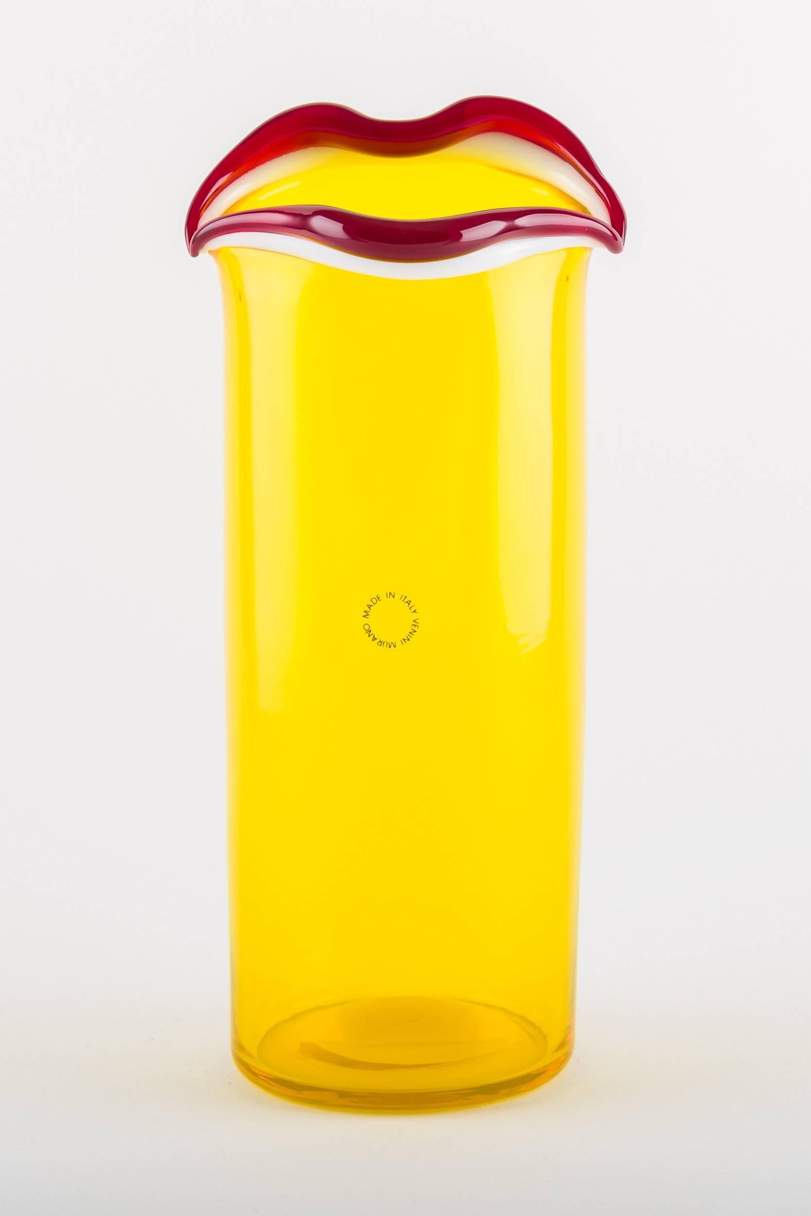 Sorriso is the result of the last series of vases designed by Fulvio Bianconi for Venini at the end of the 80s.
It is a mouth-blown glass vase, on which is applied a milk-white smile with red lips.
The body of the vase is itself made of yellow