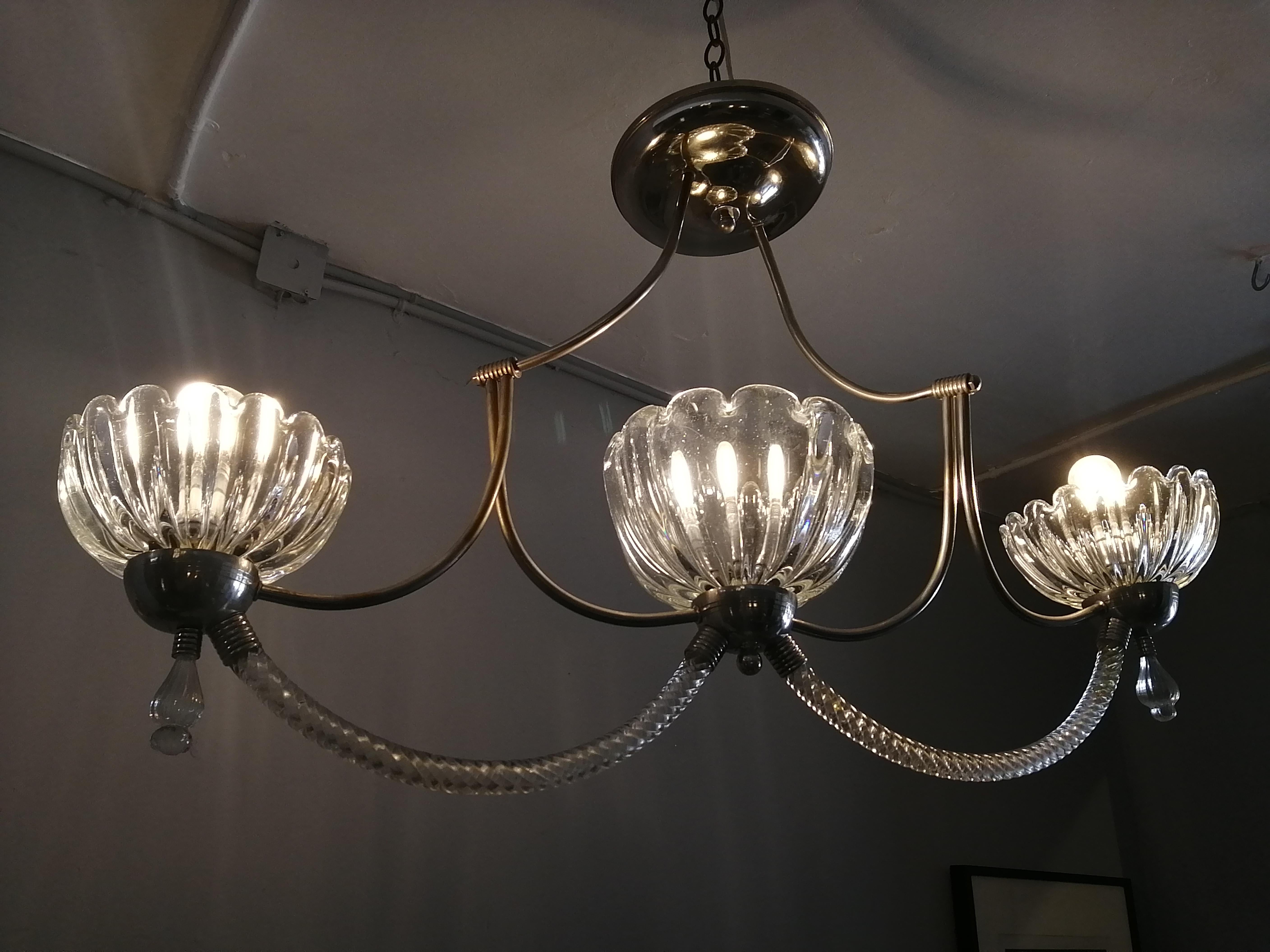 A 1950s Murano glass and brass 3-light chandelier by Venini. The swirl arms join 3 gadrooned screens underneath. A brass lineal structure joins the fixture to the top. Marked 