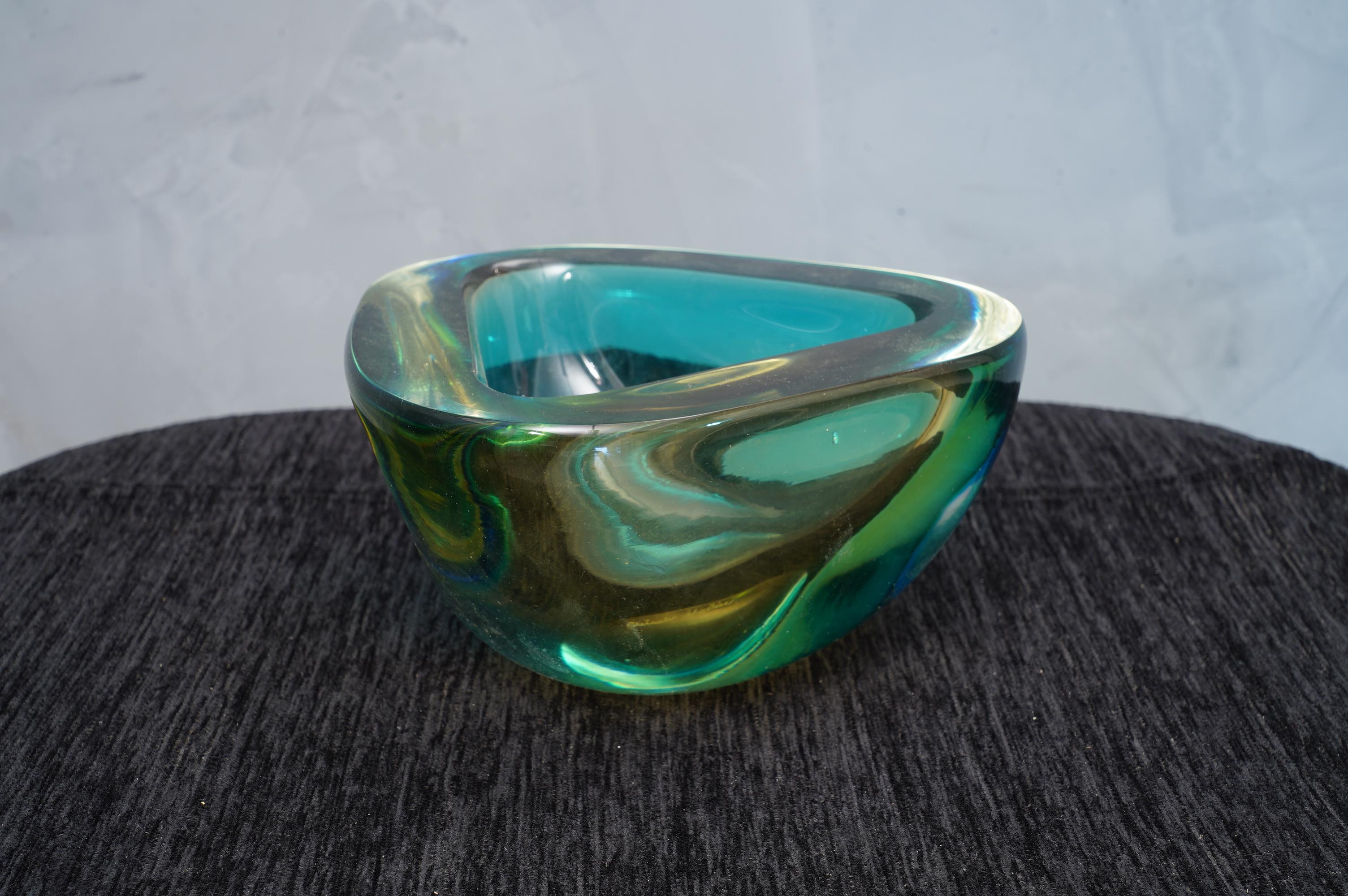 Ashtray formed by a particular submerged glass, signed Venini, with a wonderful double green and yellow color.

The ashtray is in Murano glass, triangular in shape, and with a particular transparent green and yellow color. The signature is placed on