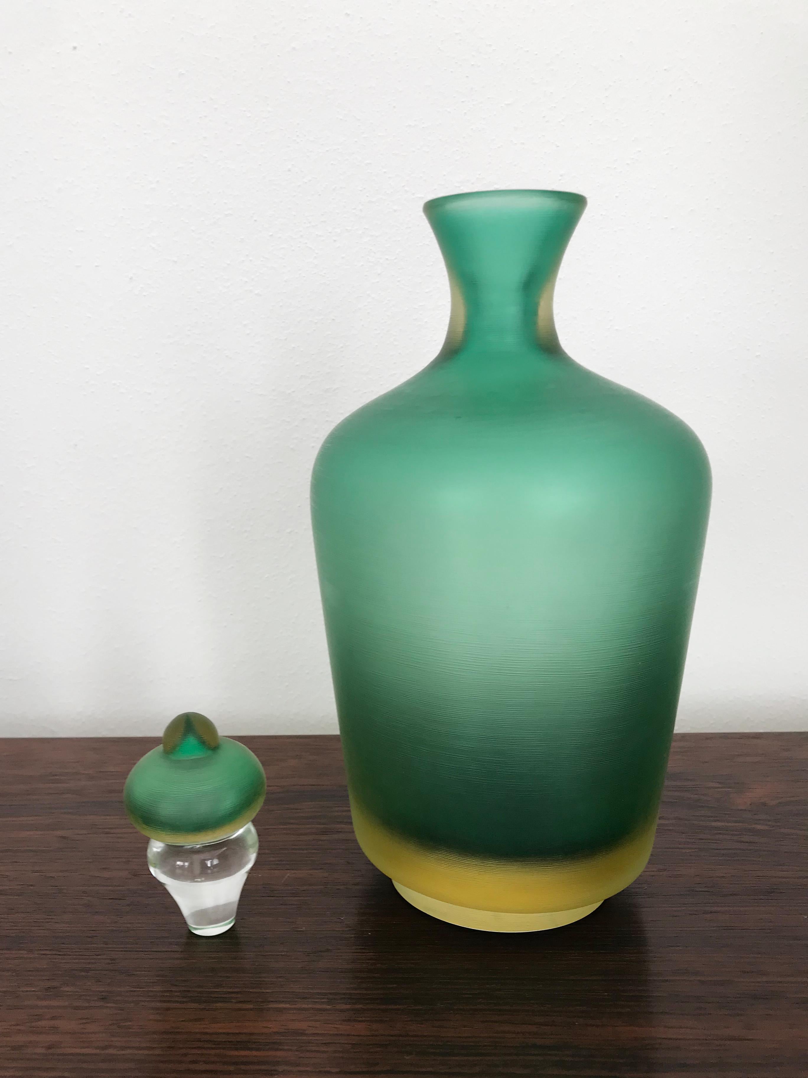 Italian glass bottle vasec with stopper, “Incisi” series, in two-color submerged glass with surface entirely worked by grinding produced by Venini Murano, Venini trademark 2004 engraved on the base.
Limited edition.
Please note that the item is