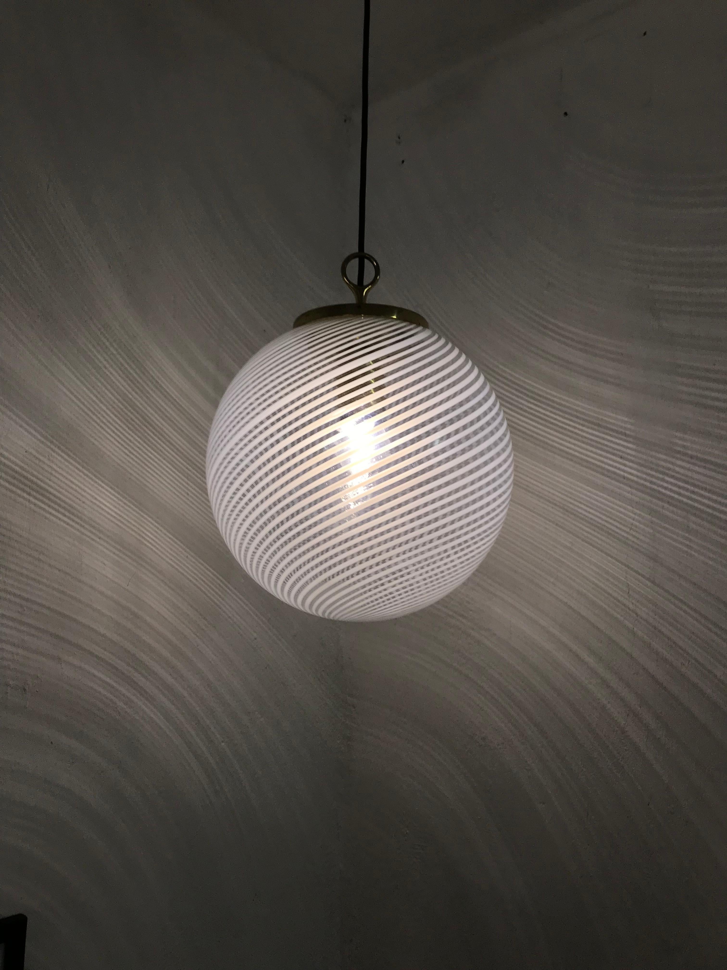Beautiful pendant light in sphere shape, in clear and white striped hand blown Murano glass, style of Venini, circa 1970's.

Please look at the photos to really appreciate the beautiful shadow this kind of lamps cast.
Measures: Diameter is 30 cm.

 