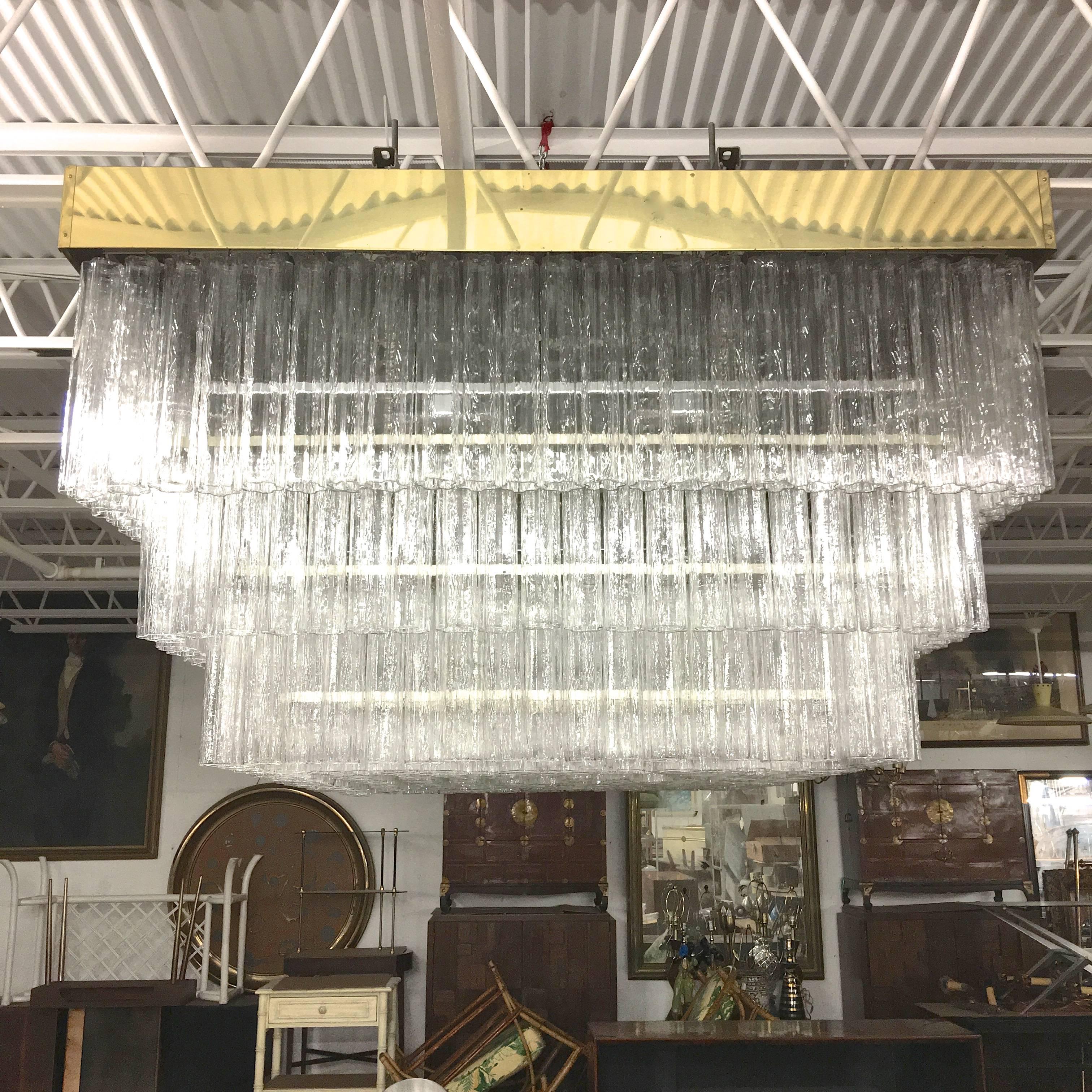 Monumental 1970s vintage Venini Tronchi crystal ceiling mounted chandelier from a Boston area hotel lobby. Six foot six inches square. Three tiers. four different size crystals. Brass banded square pan frame with mirror polished stainless steel