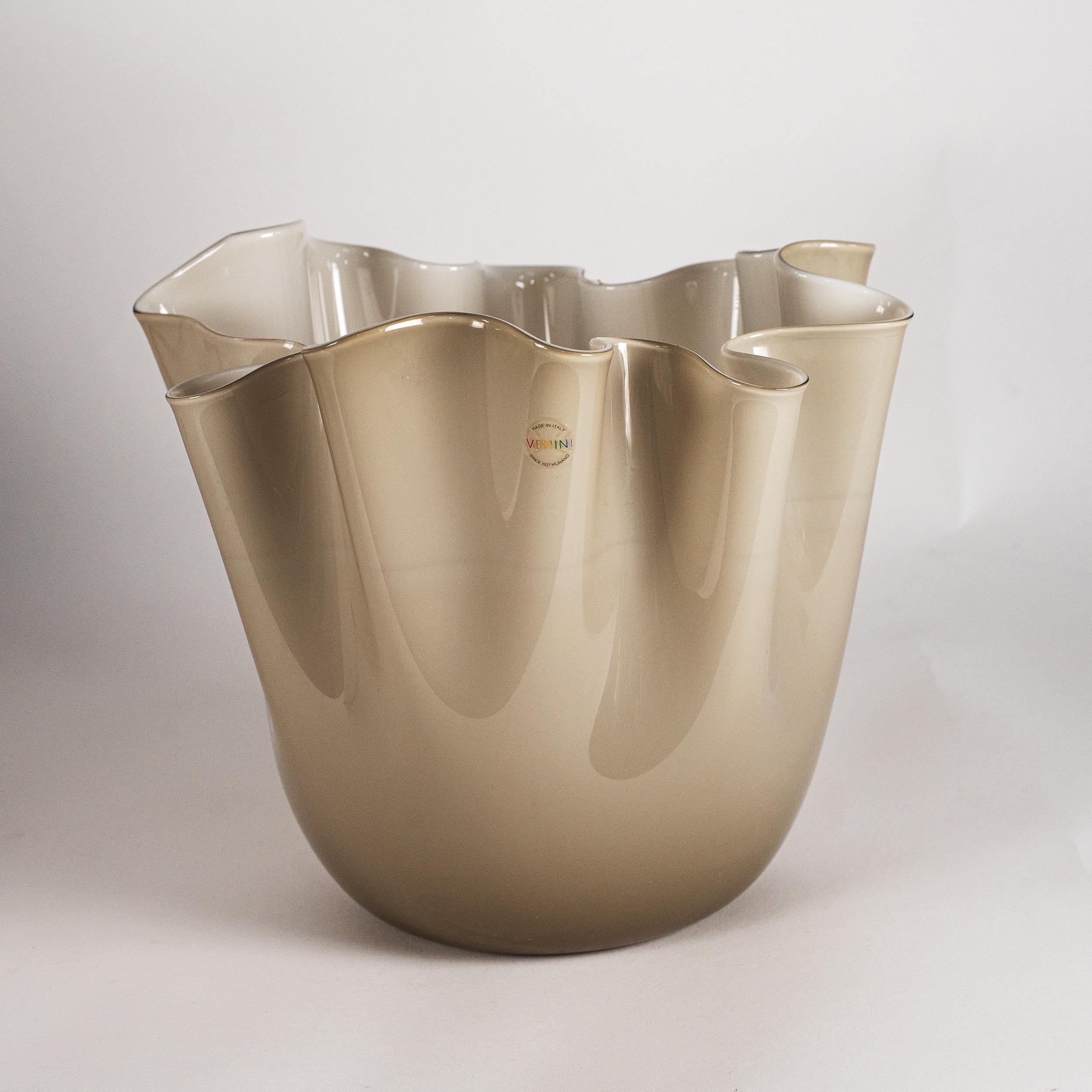 L'iconico vaso Fazzoletto di Venini, modello 700.02, in vetro opalino grigio. Soffiato e rifinito a mano dai maestri vetrai di Murano, con il caratteristico bordo ondulato 