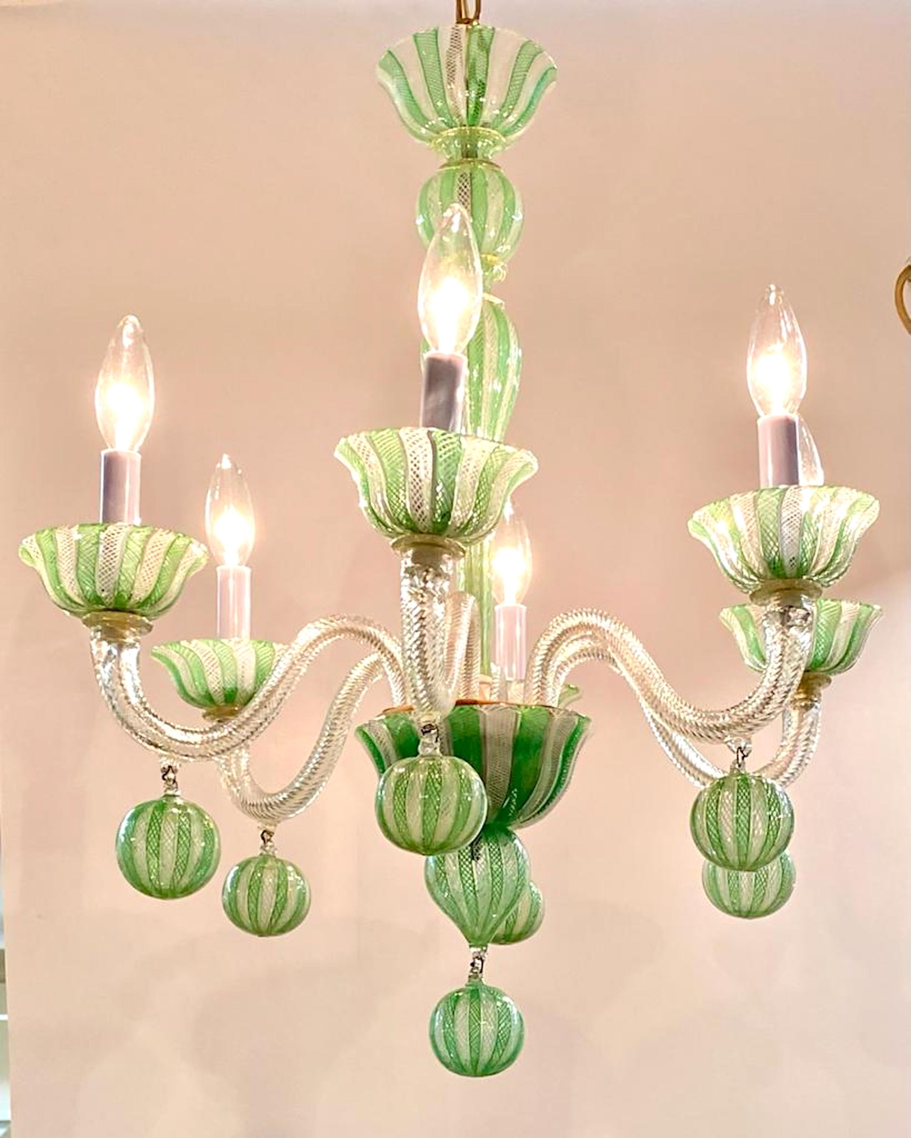 A lovely and unique design 1950s Venetian glass chandelier attributed to the famous glass house Venini. The chandelier is hand blown in clear glass with criss crossing lines in white and green glass. The criss cross design, known as reticello, is