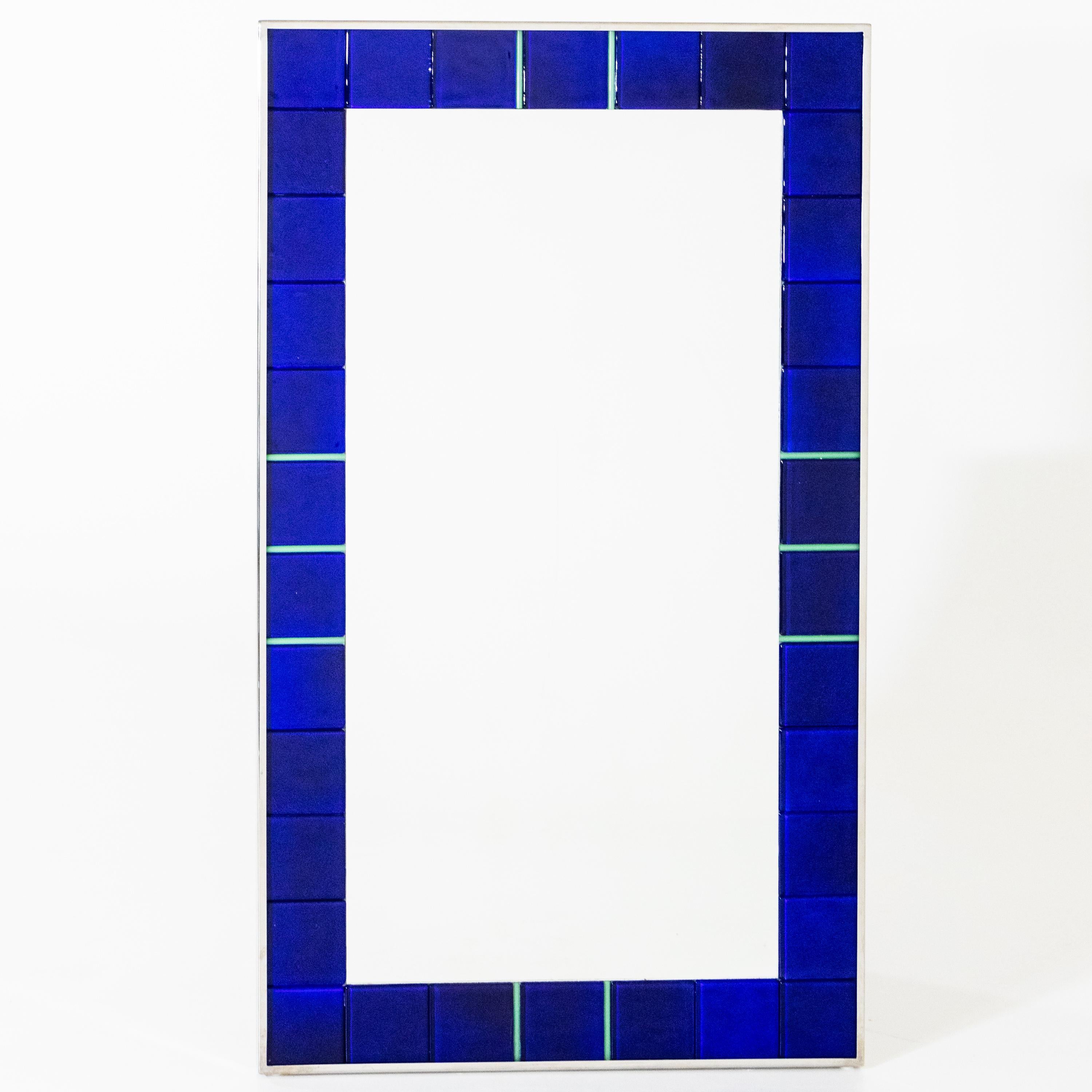 Large wall mirror in smooth metal frame with wide border of blue, glass panes with green dividers.