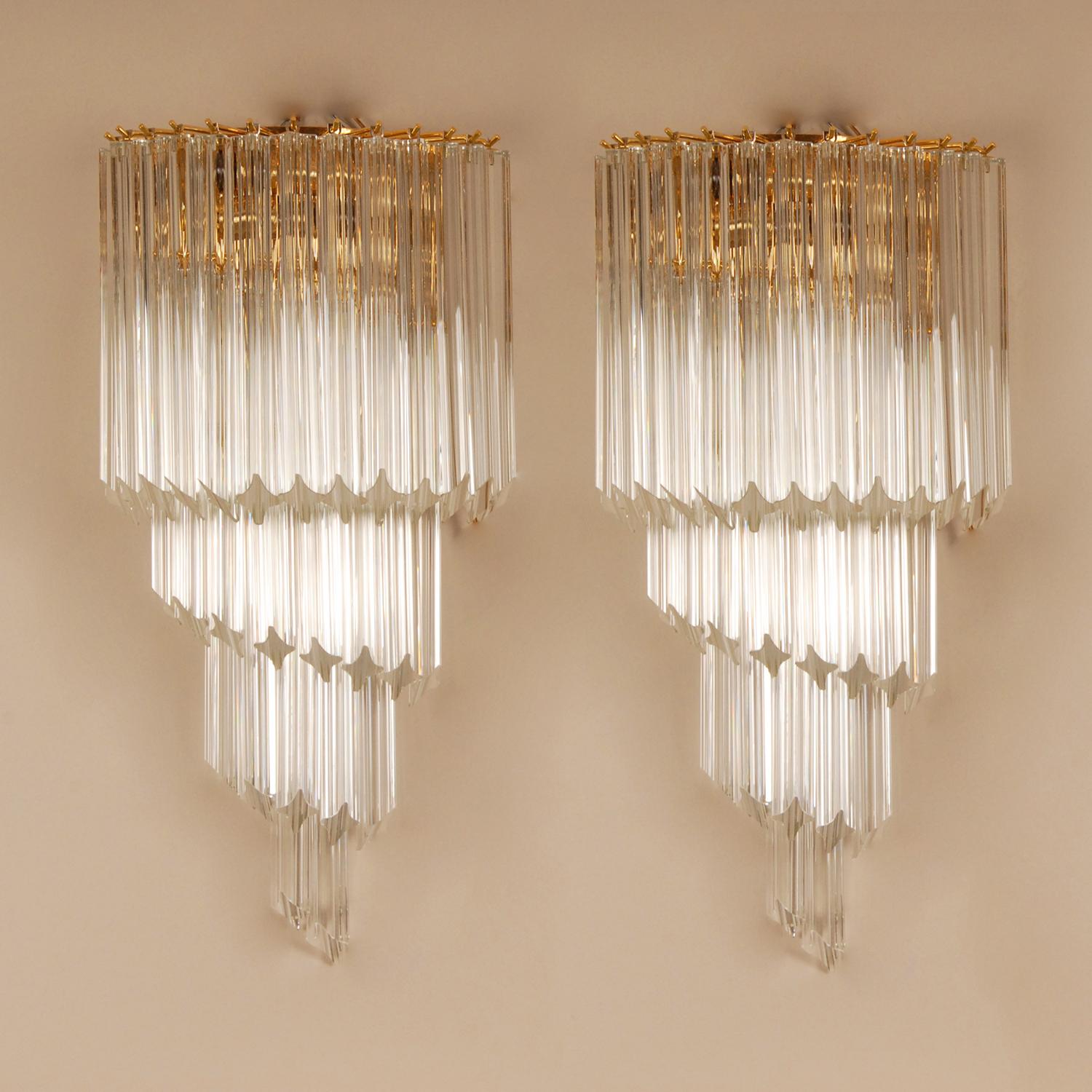 Venini wall sconces Italian wall lamps.
4 Tier gold gilt frame with blown Murano glass quadriedi prisms.
The glass tetrahedron tubes / Quadriedi Prisms are conducting the light and creating a very special effect
To optimize the reflection effects of