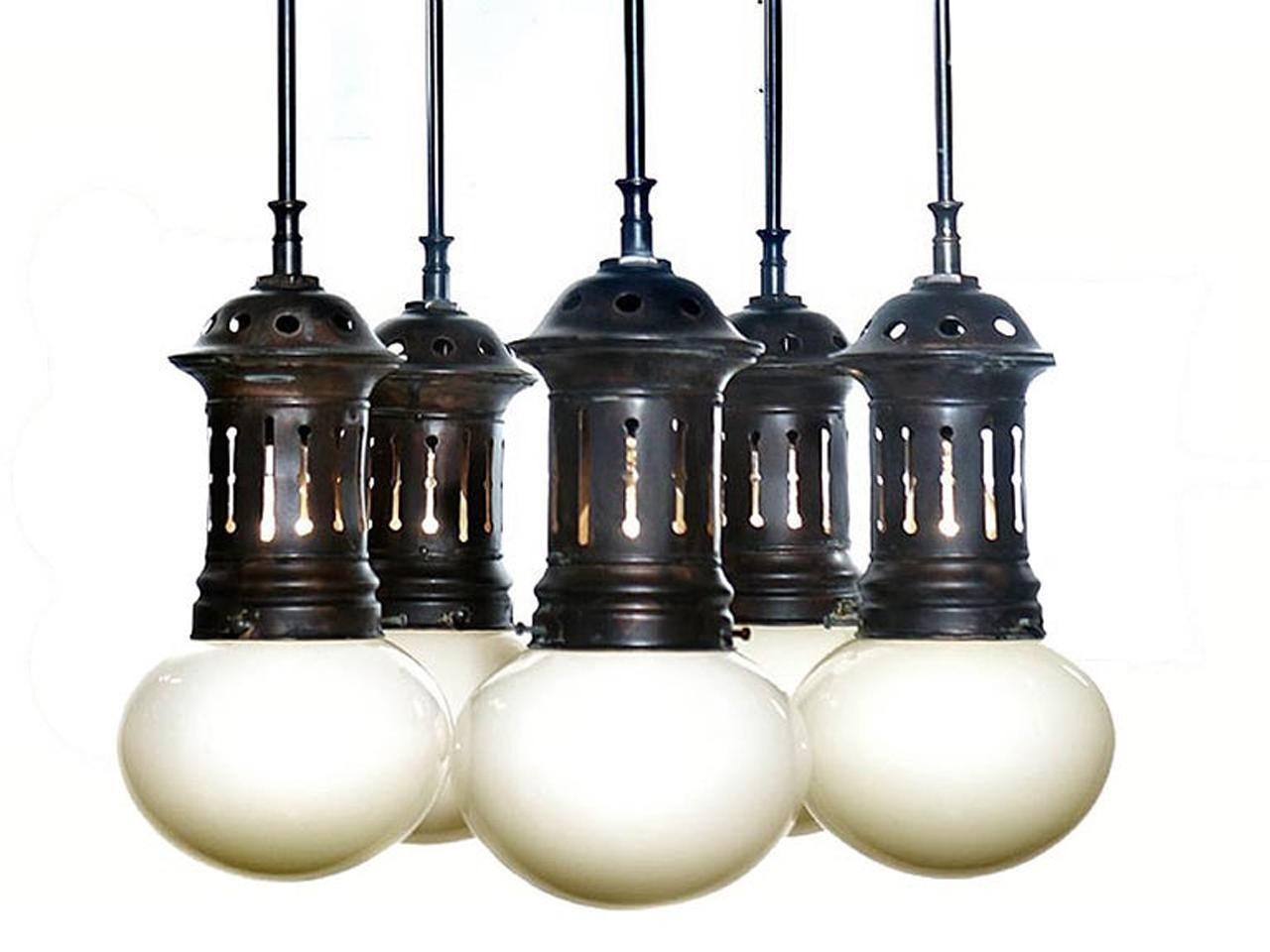 Stroll into New York's Park Avenue armory and you will see the striking multi-globe lamps in the front lobby. This amazing chandelier has that early municipal look. These early and elegant bun shaped hand blown shades are Vaseline over white