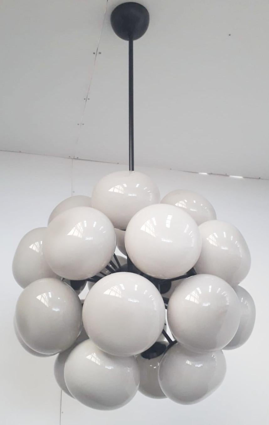 Lampadario Sputnik italiano con 24 paralumi in vetro di Murano color crema montati su una struttura in metallo con finitura verniciata a polvere nera opaca / Disegnato da Fabio Bergomi per Fabio Ltd / Made in Italy
24 luci / tipo E12 o E14 / max 40W