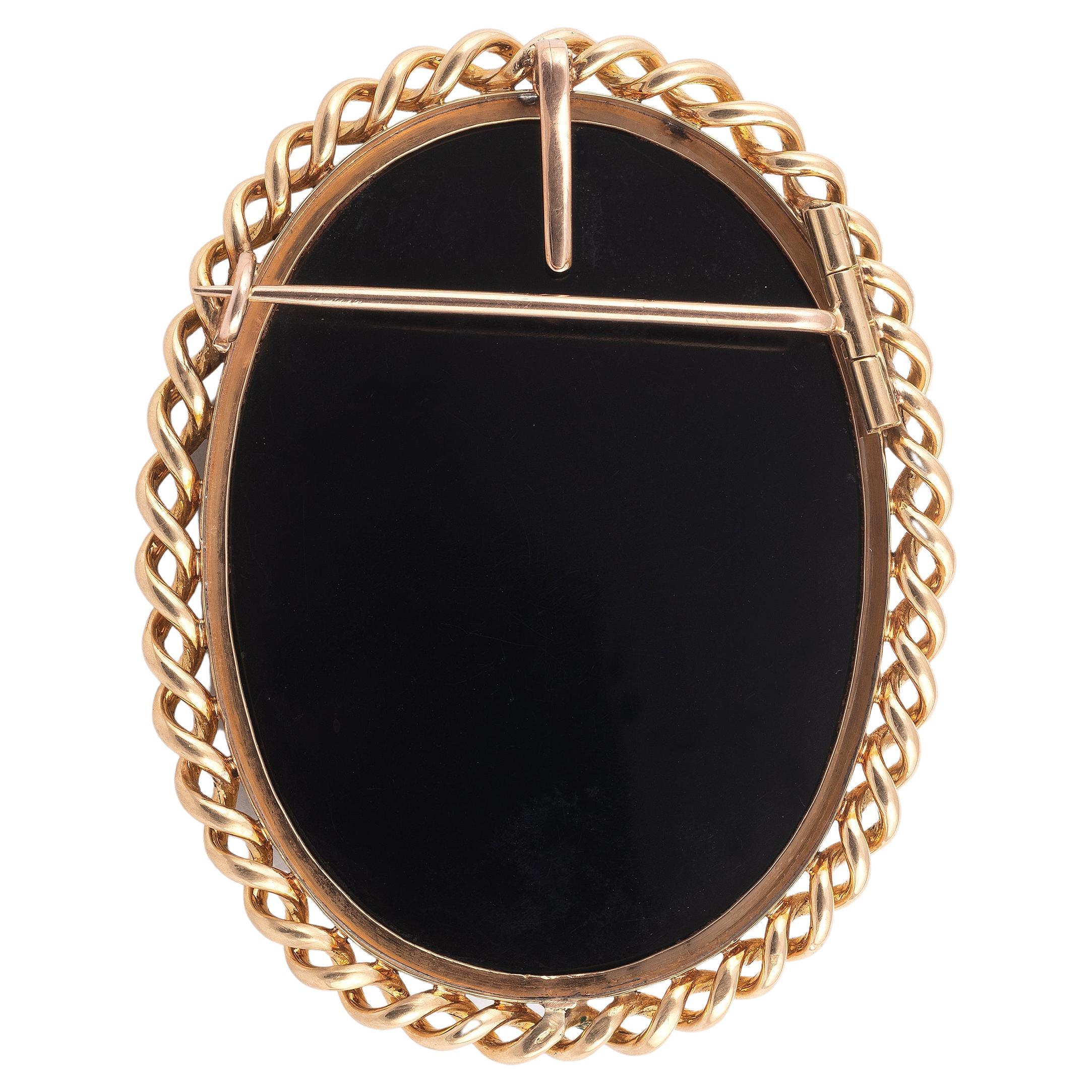 Oval brooch/pendant in 18kt yellow gold, the center decorated with an onyx cameo depicting a Venus bust in profile wearing emerald and diamond highlight jewellery. 19th century French work. Height: 6.3 cm - Gross weight: 49.8 g