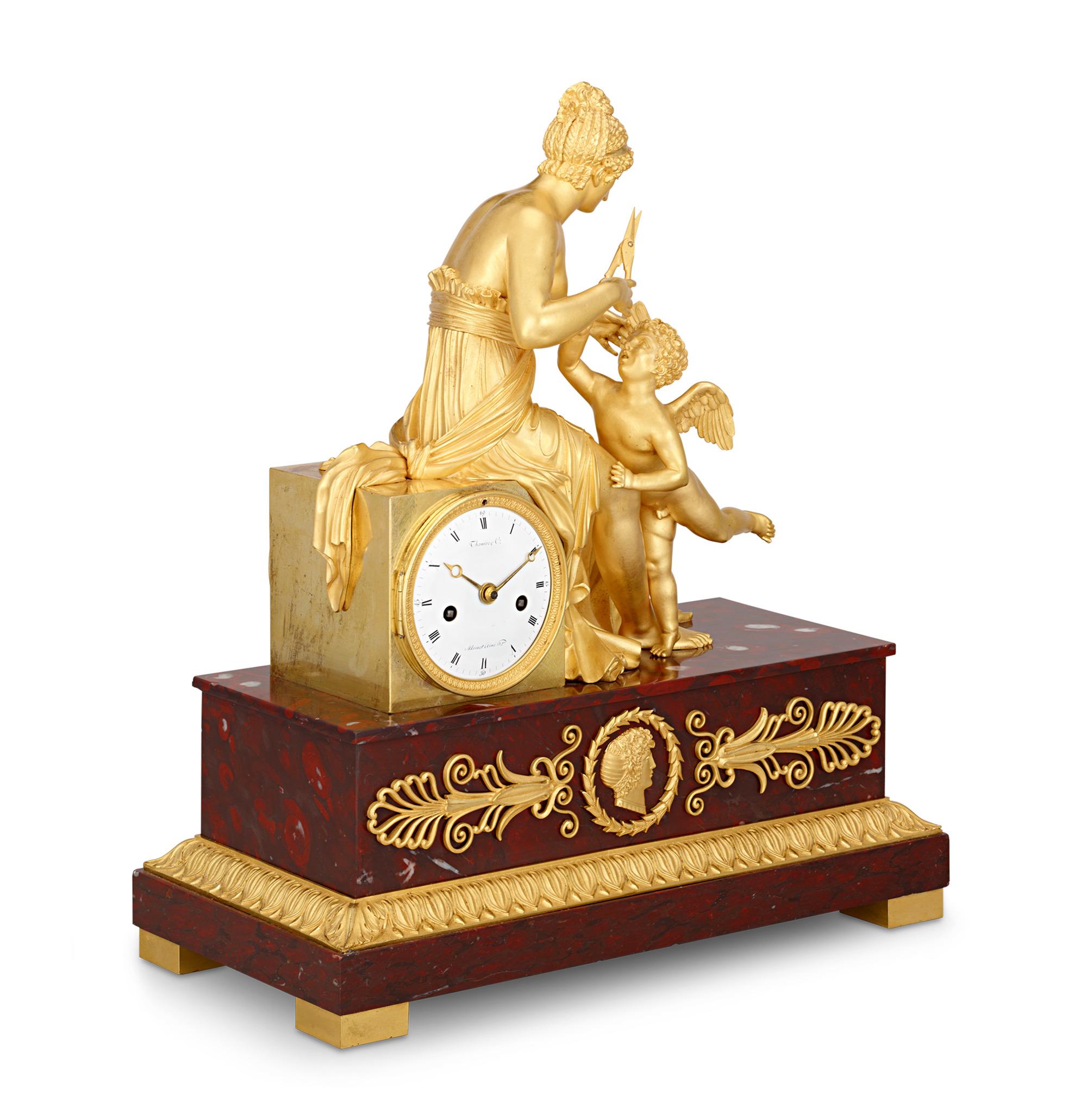 This splendid Empire gilt bronze French mantel clock, signed on the dial by bronzier Pierre-Philippe Thomire and watchmaker Louis Moinet, features an exquisitely detailed scene of Venus clipping the wings of Cupid on a base of red cherry marble.