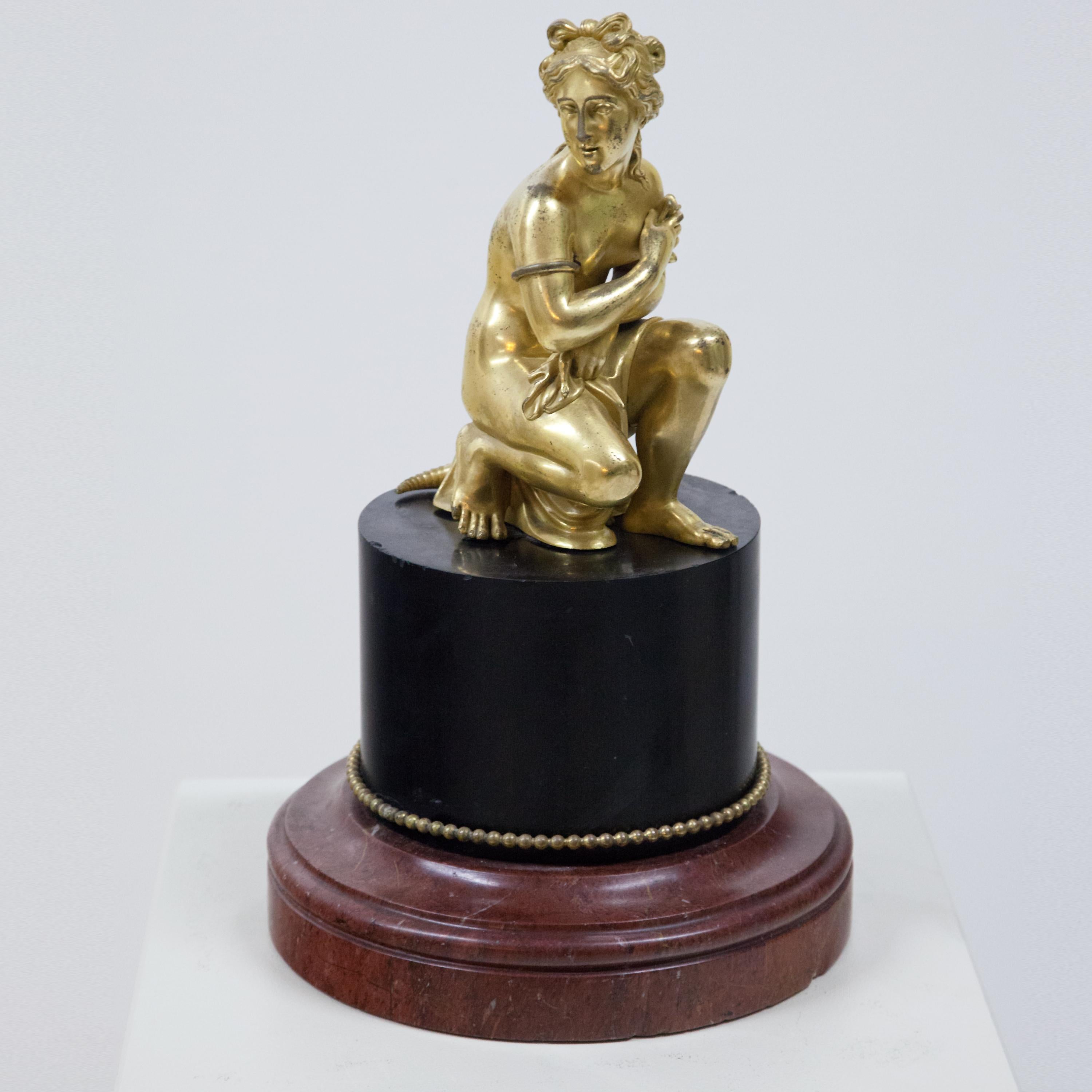 Representation of the sitting Venus with turtle after the original by Antoine Coysevox (1640-1720, Louvre 1686) on a round black truncated column with red profiled base. Marble, bronze fire-gilt. (Measures: Height plinth 19 cm).