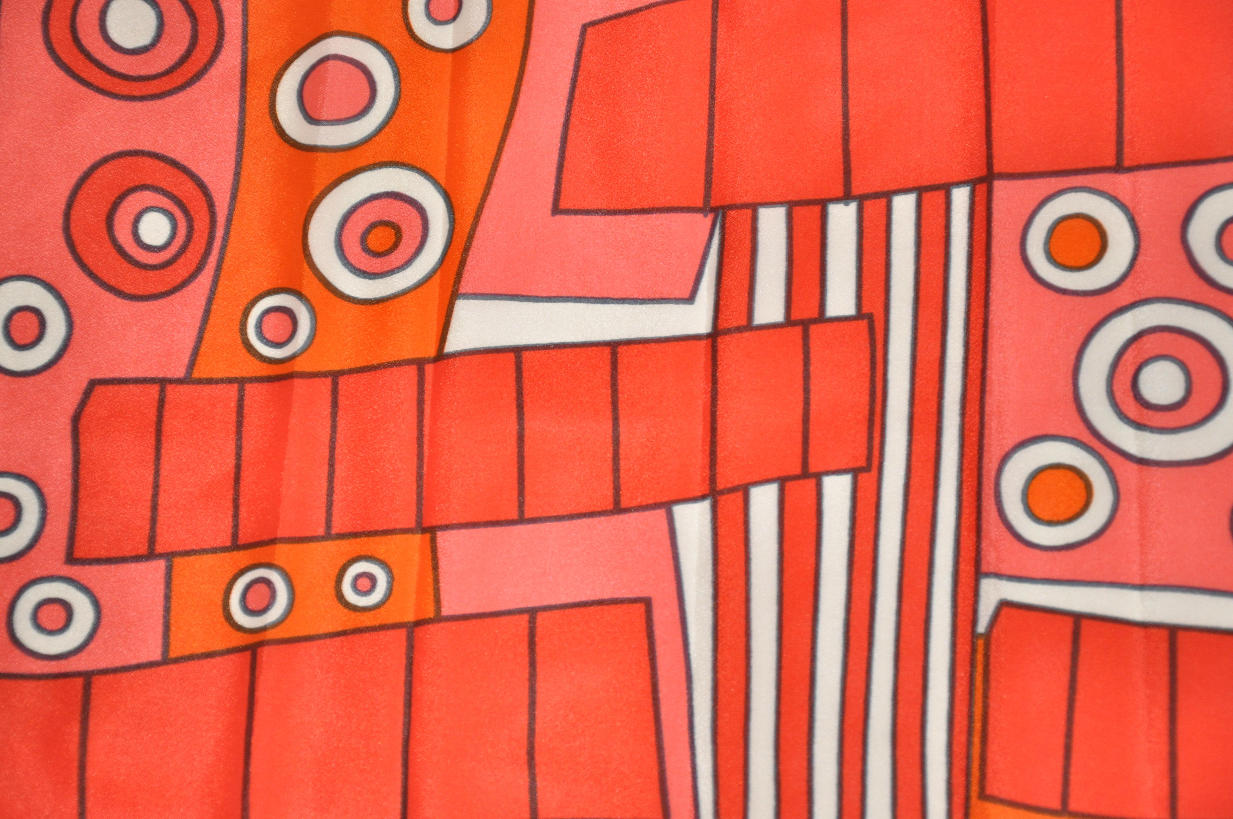        L'écharpe Vera merveilleusement audacieuse à l'imprimé abstrait néon mandarine et rouge accentué par des bords roulés à la main mesure 43 pouces sur 14 pouces. Fabriqué au Japon.