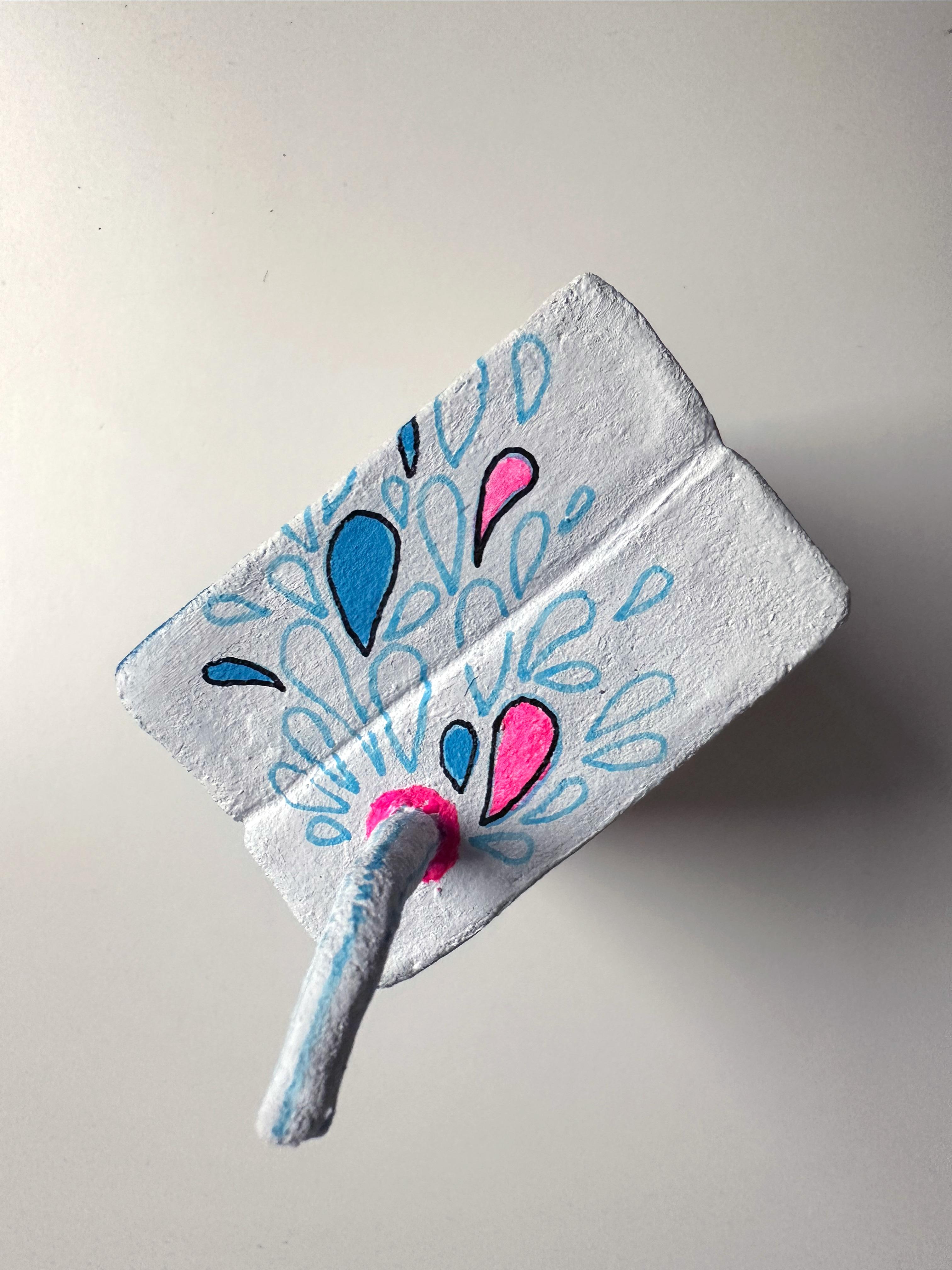 Die kleinformatige Tonskulptur in Acryl erforscht den Konsum anhand eines Saftkartonobjekts, das Zucker- und Pillenbilder in einer verschneiten emotionalen Landschaft vereint.
Diese von Hand modellierte und mit Acryl bemalte Tonskulptur hinterfragt