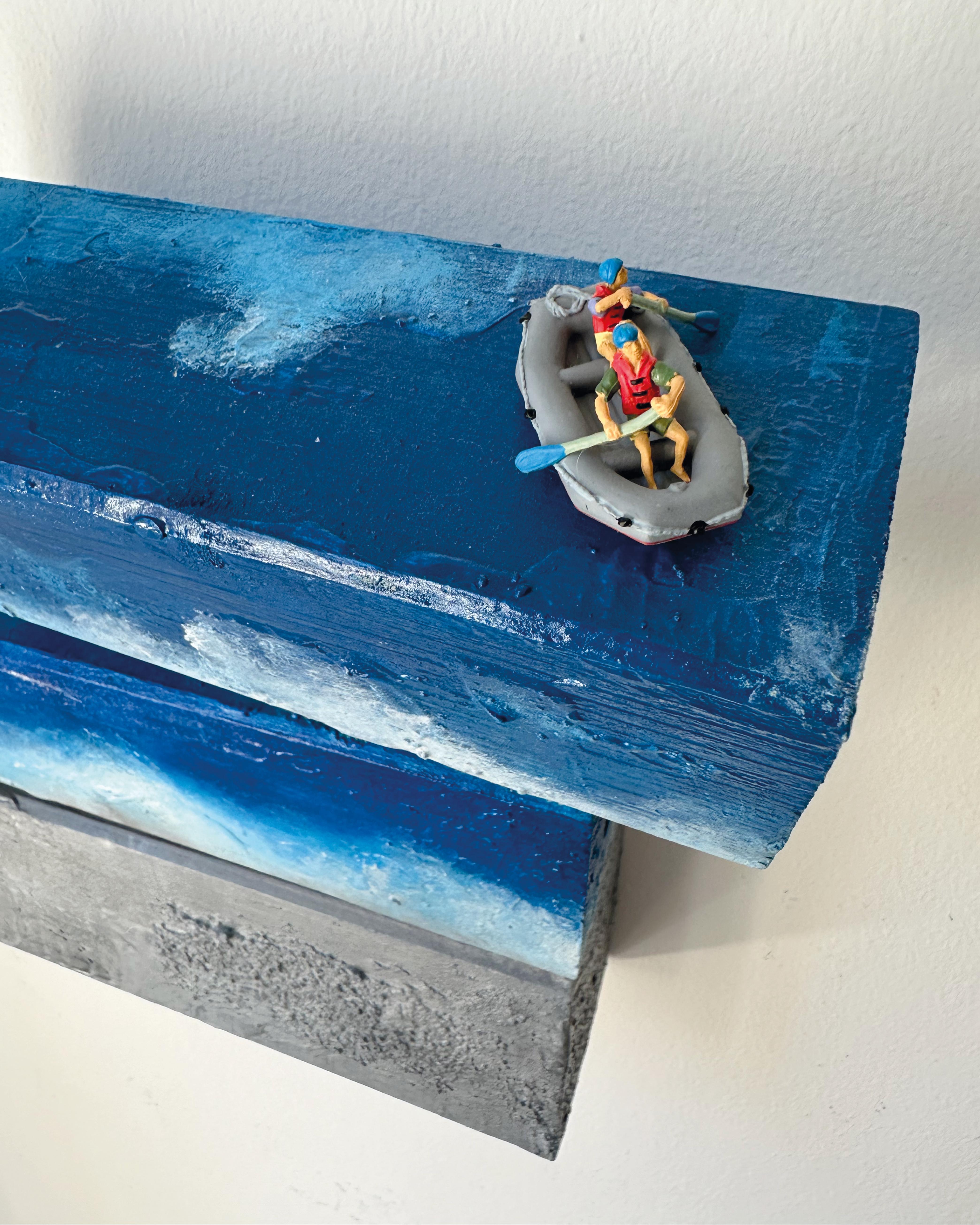 This evocative wall sculpture by Vera Vizzi, titled VITA, forms part of the artist’s ongoing exploration of maritime themes and human vulnerability. Crafted in mixed media on reclaimed wood, the piece presents a poetic seascape made of three stacked