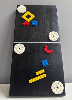 Escultura mural modular de bloques de construcción en colores primarios sobre panel negro