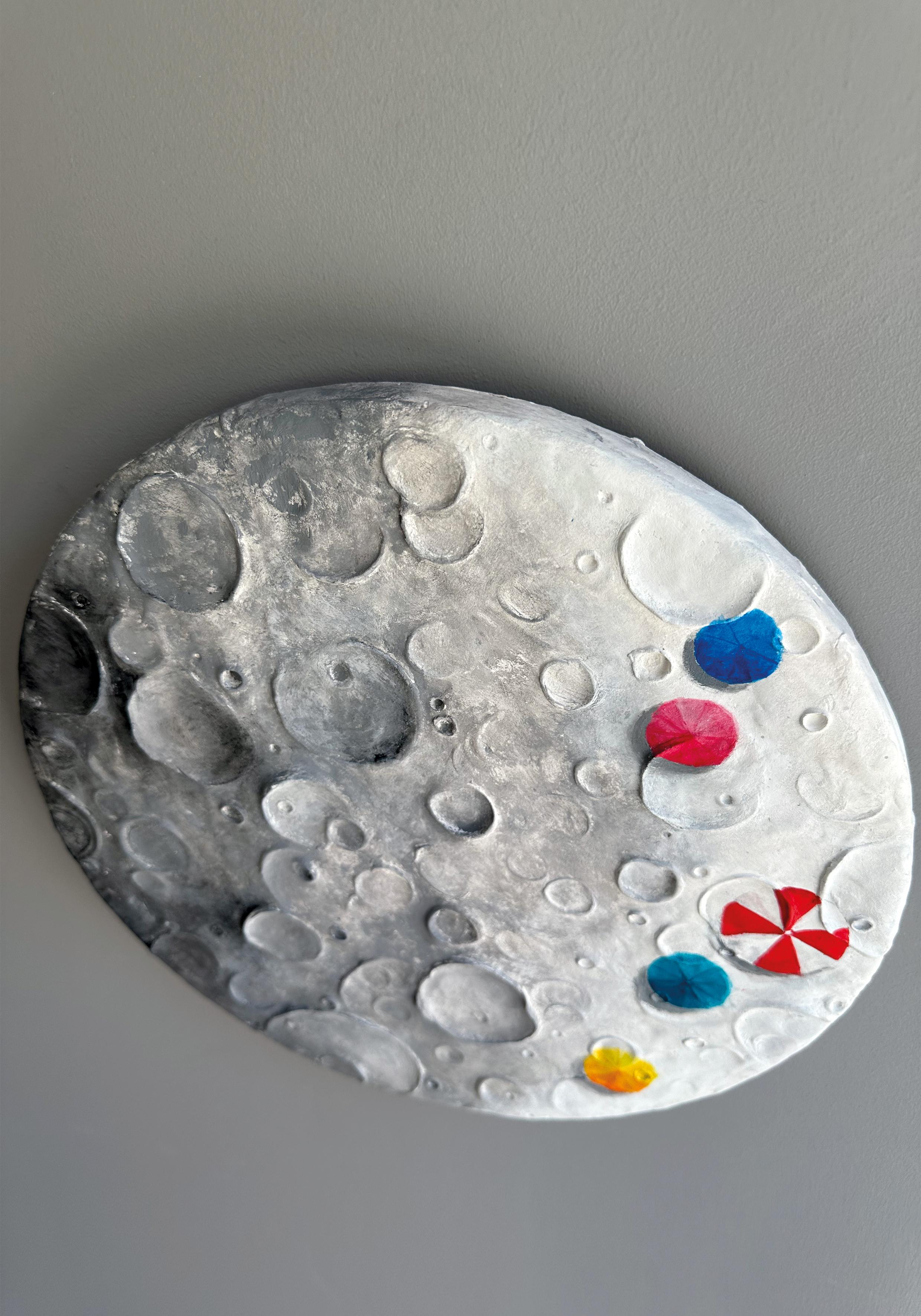 Fase es una escultura mural contemporánea de Vera Vizzi que fusiona la topografía cósmica con la intervención simbólica. Realizada en arcilla de modelar y acrílico sobre una base circular de madera de abeto (30 cm Ø), la pieza evoca una superficie
