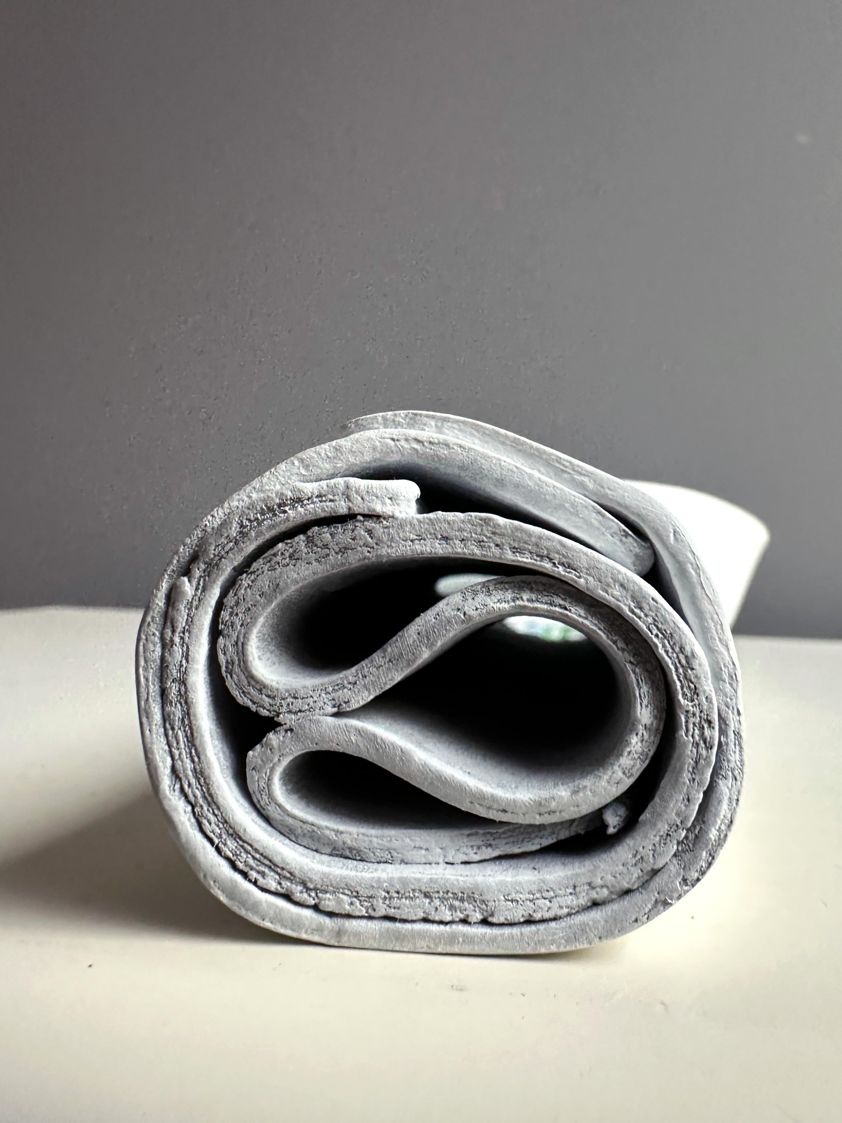 Wandskulptur aus selbsthärtender Paste mit einer bemalten Innenseite, die erzählende Blumen und folkloristische Motive zeigt.

ENJOINT ist ein gefaltetes Wandobjekt, das sowohl als Gefäß als auch als Bühne fungiert. Die Außenseite zeigt eine