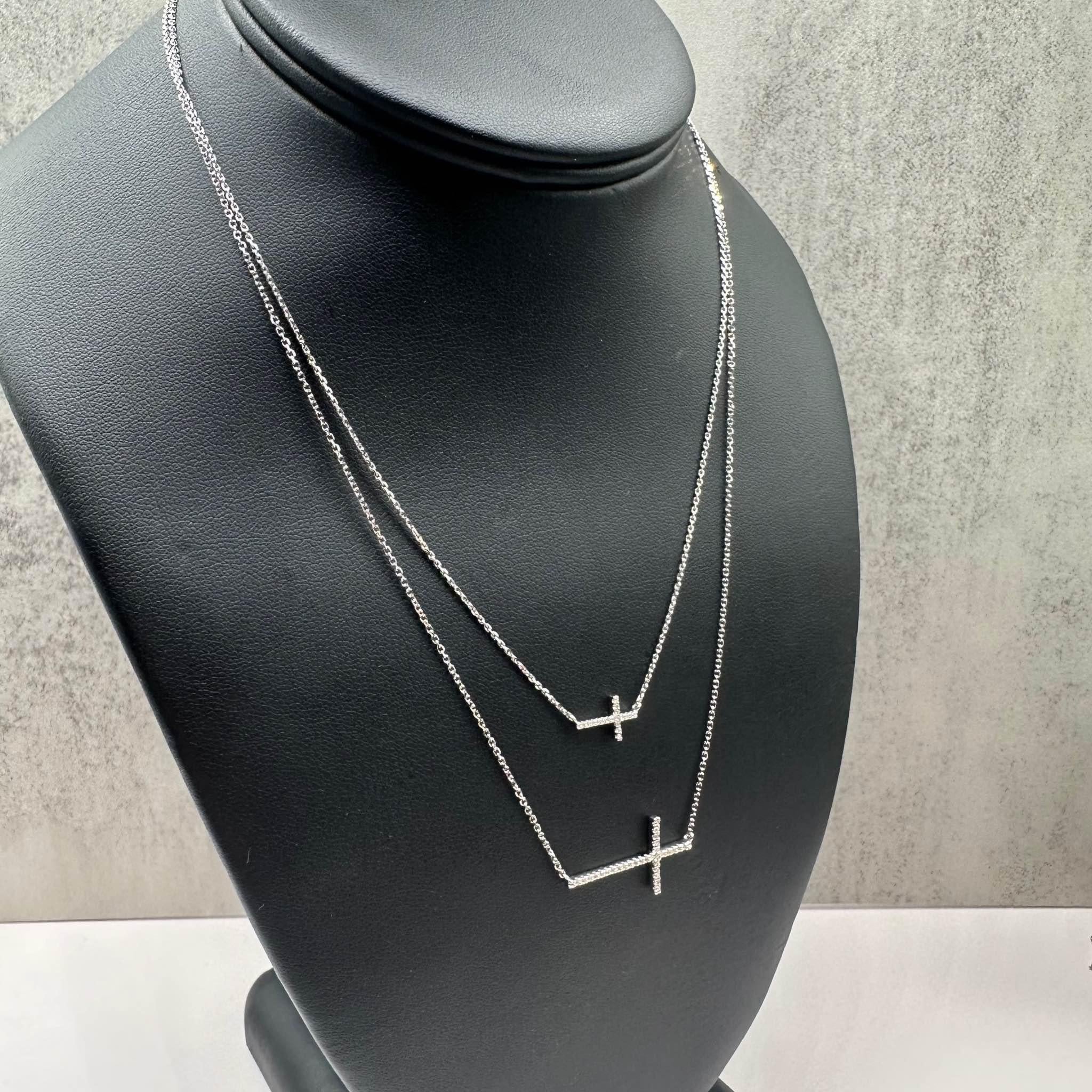 This stunning Designer Vera Wang Love Collection Diamond Double Strand Sideways Cross Pendant in 10K white gold features 0.20ctw of natural HI I1 round diamonds, adding a touch of brilliance to the sideways cross design. The longer layering necklace