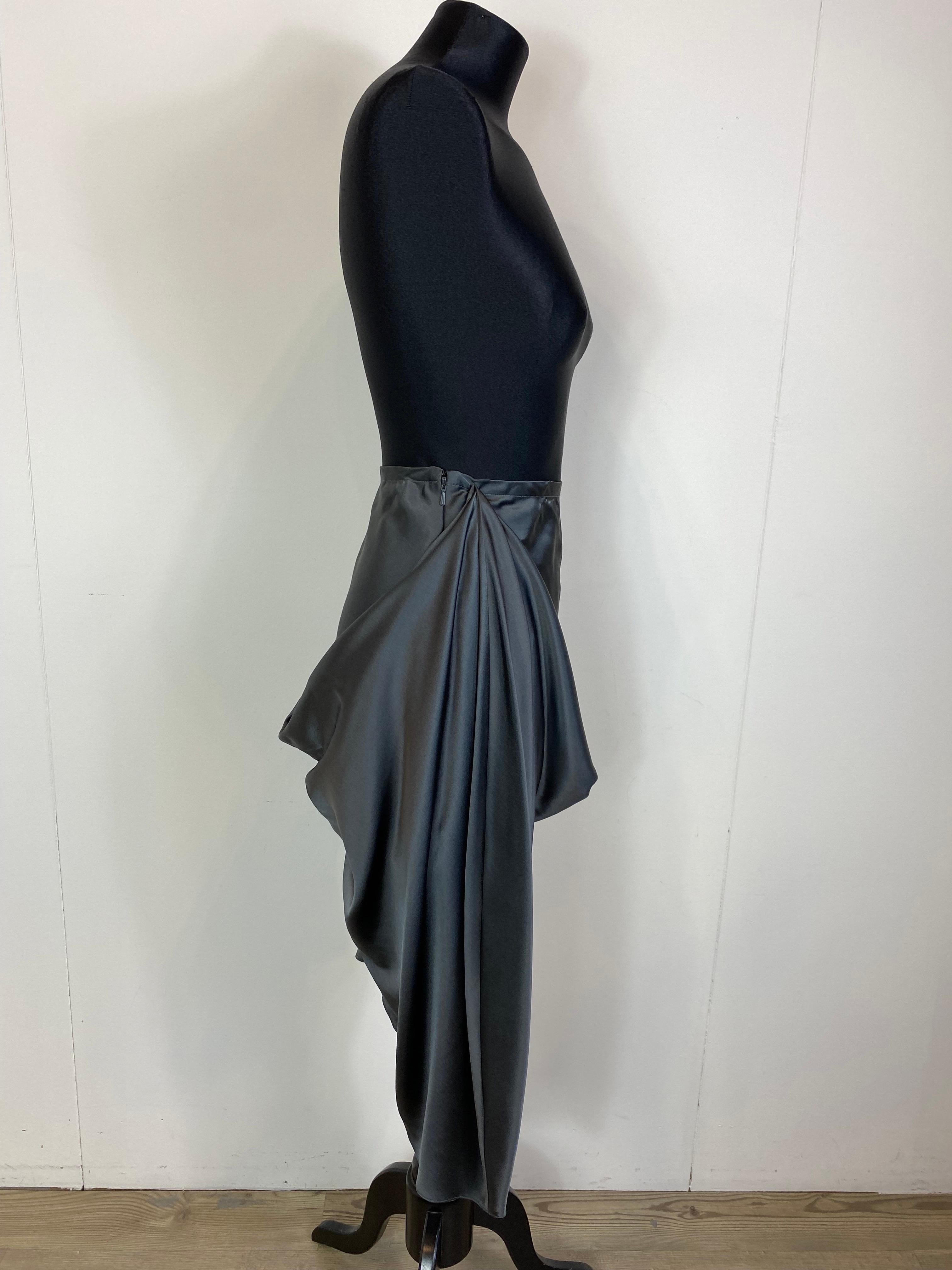 Gonna asimmetrica in seta grigia di Vera Wang.
Taglio sbieco con drappeggio sul davanti e sul retro.
Chiusura con zip invisibile sul lato.
Nuovo, con etichetta.
Taglia 10/44
Vita 43 cm
Lunghezza 72 cm