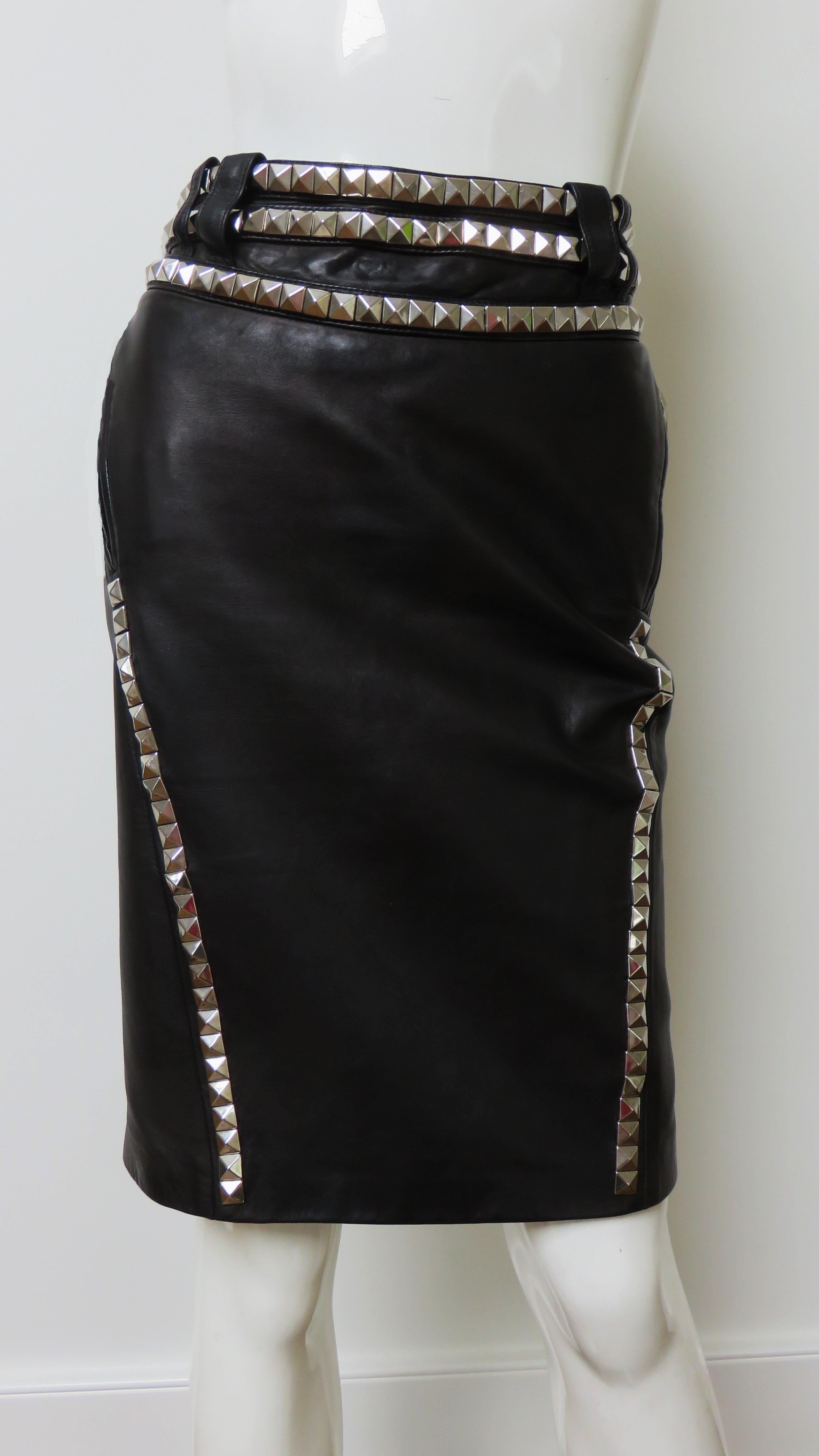 A fabulous black leather skirt from Versace.  It is pencil style with rows of silver metal studs around the waist and along angled front seaming into which zipper pockets at hip level are incorporated. The back of the skirt is comprised of 10