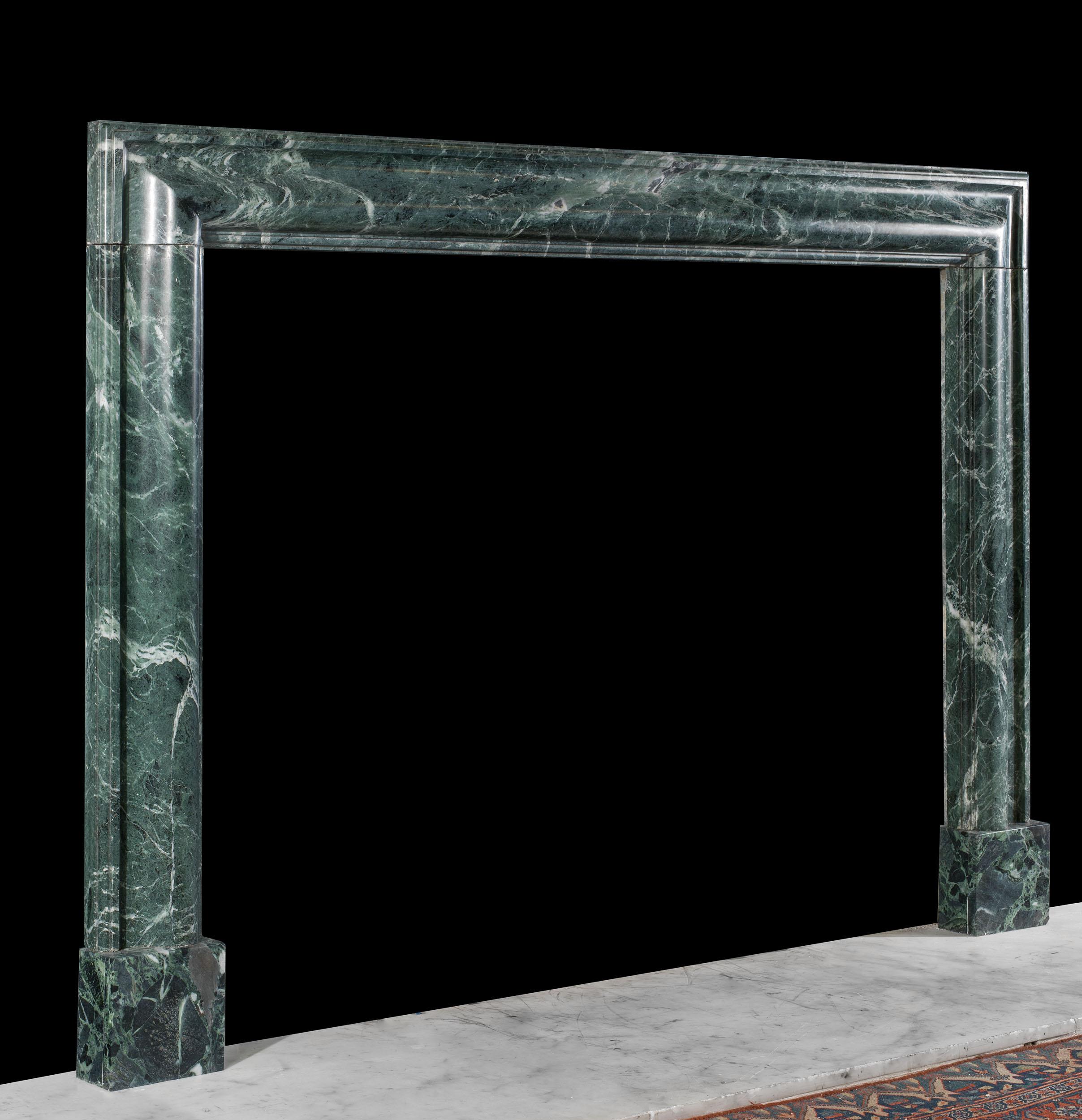 An antique bolection fireplace in boldly veined green verde antico marble.
English, c.1930.