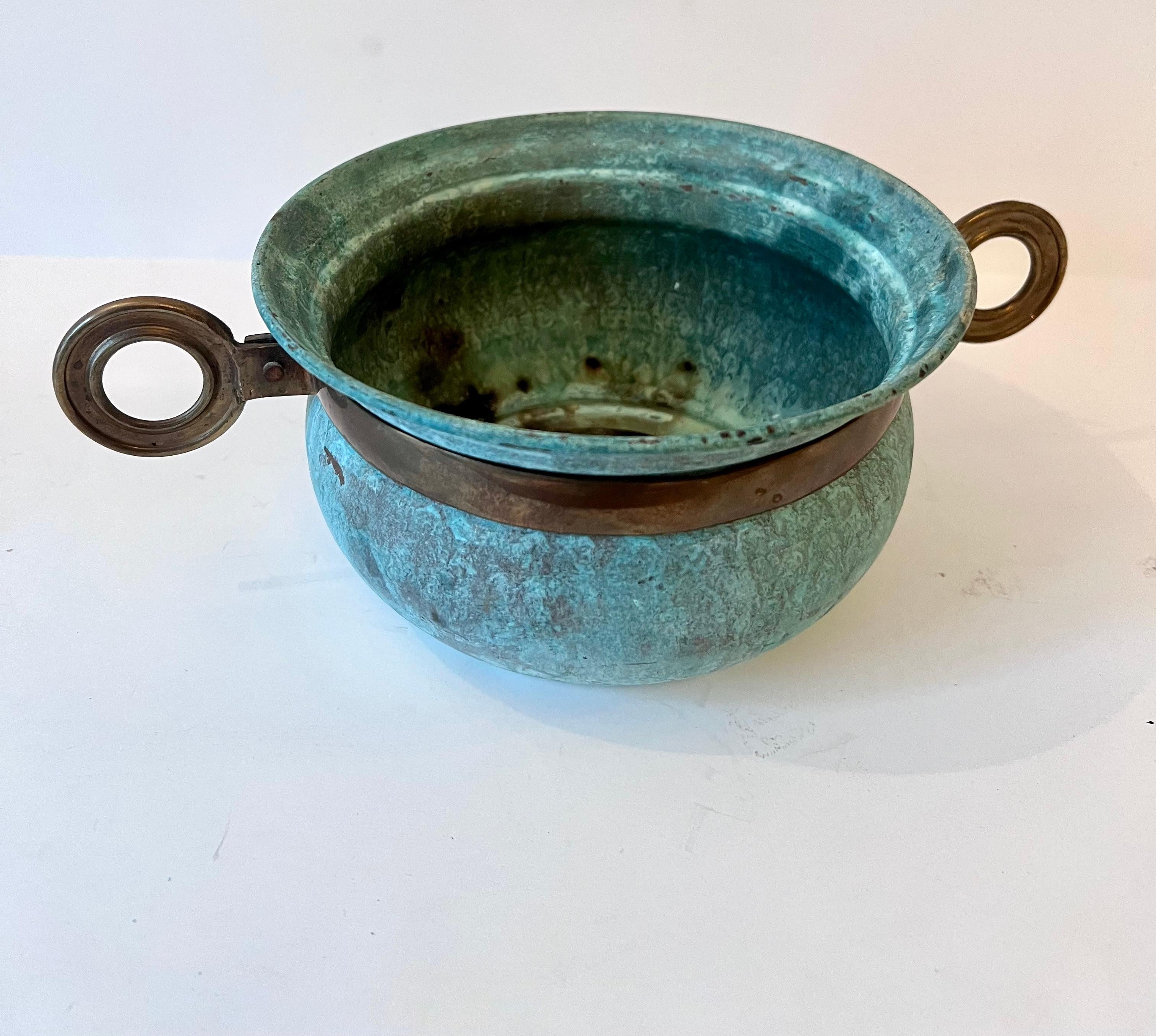 A heavily patinated verdigris bowl with unique brass details - rings on either side of the piece - compliment to many settings.

Could be used on a console, a cocktail or side table and even to hold pieces on the kitchen counter.