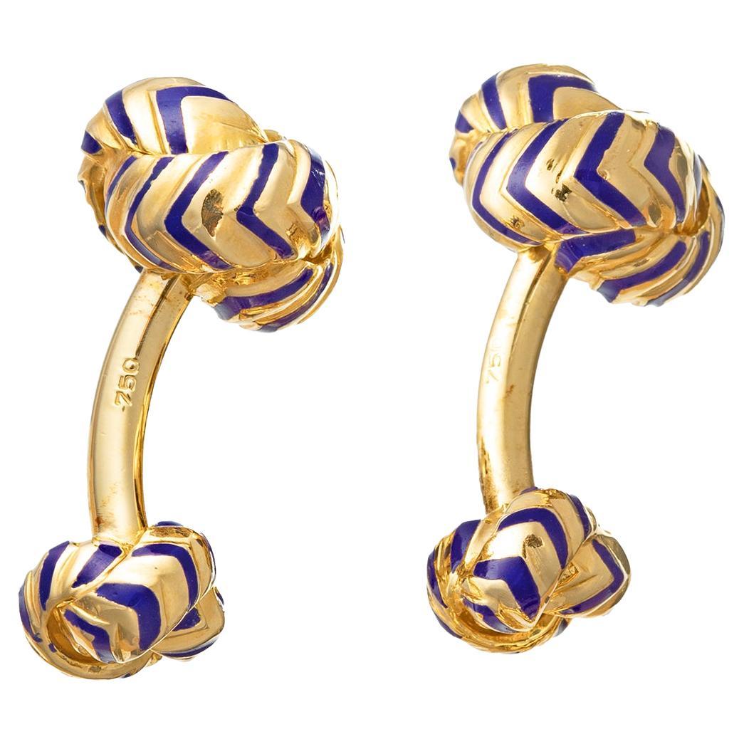 Statement knot cufflinks by Verdura in 18k yellow gold with navy blue enamel stripes. Matching large and small knot design connected by a gently curved bar.  Signed 'VERDURA' '750'.

These exquisite cufflinks showcase a striking cobalt blue enamel