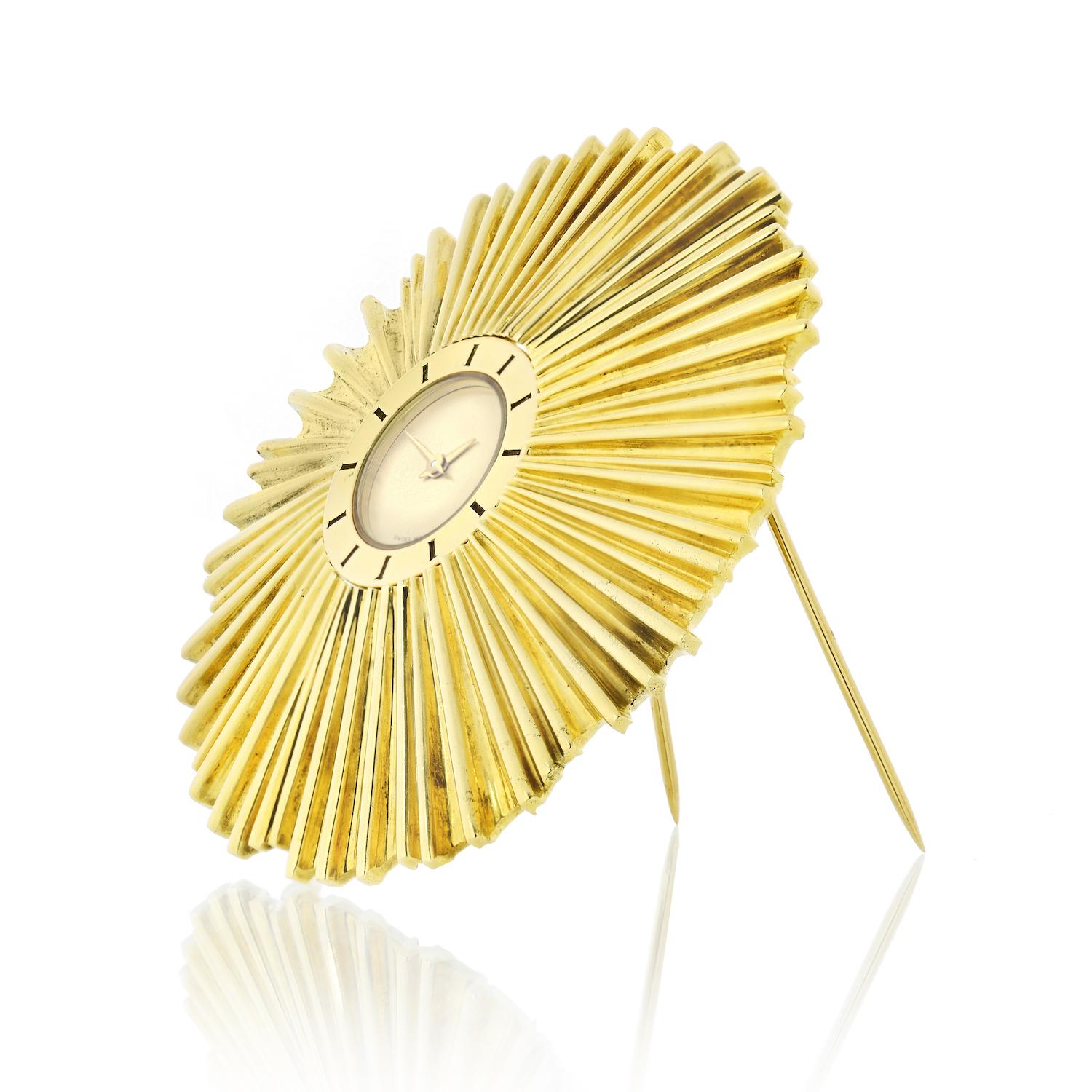 Verdura 18K Yellow Gold Watch Brooch.
Quartz movement, round dial with the round case in radiating sculpted gold surround. 

METAL: 18k yellow gold
SIGNATURE: VERDURA
MARKS: 18K
SIZE/DIMENSIONS: 5.9 cm diameter
GROSS WEIGHT: 63.3 grams