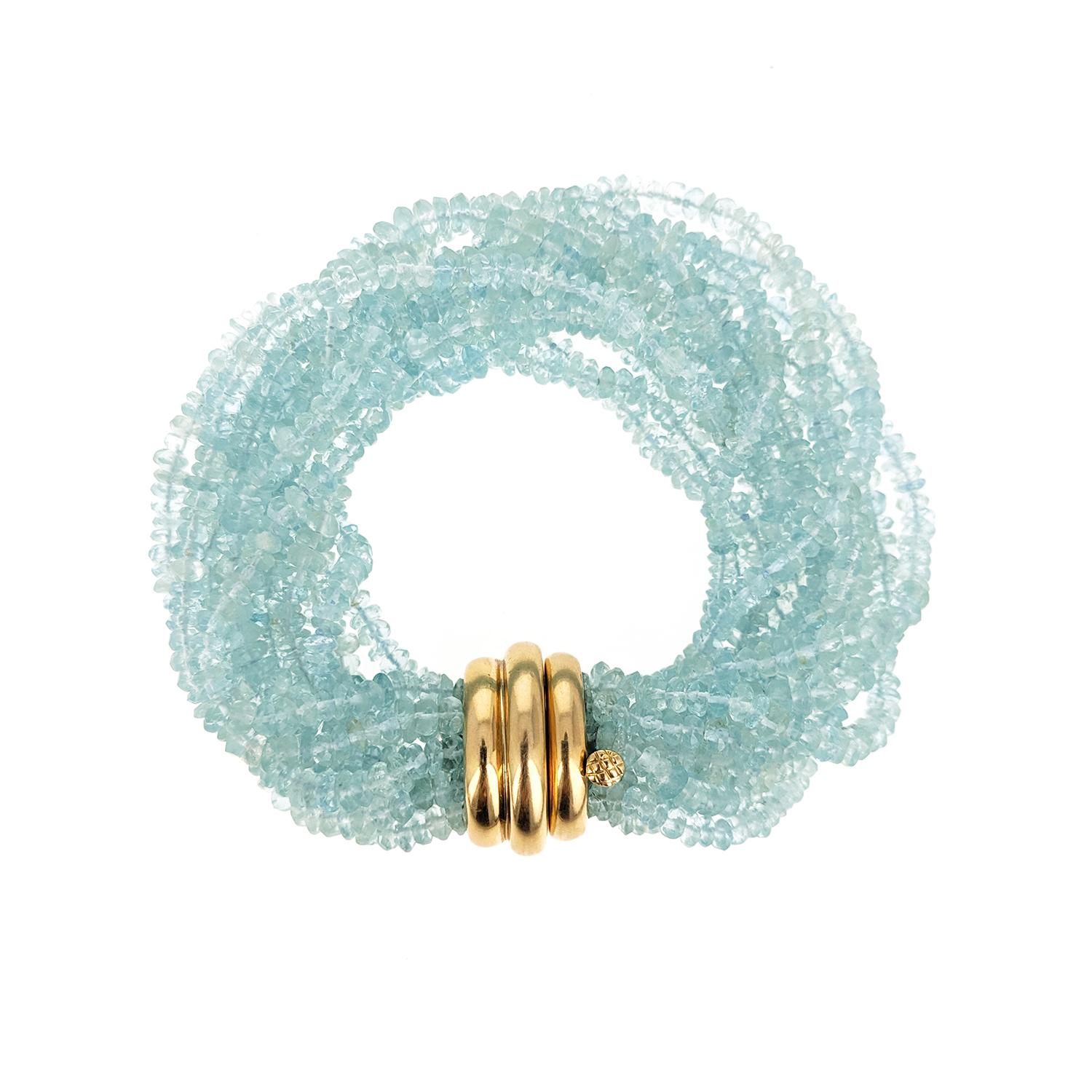 The beautiful bracelet is made of fourteen strands of faceted aquamarine beads and has a polished 18 karat yellow gold bombe clasp. It can be worn twisted or not, depending on the size of your wrist. It is signed Verdura and made in 2004. 8.5 inches