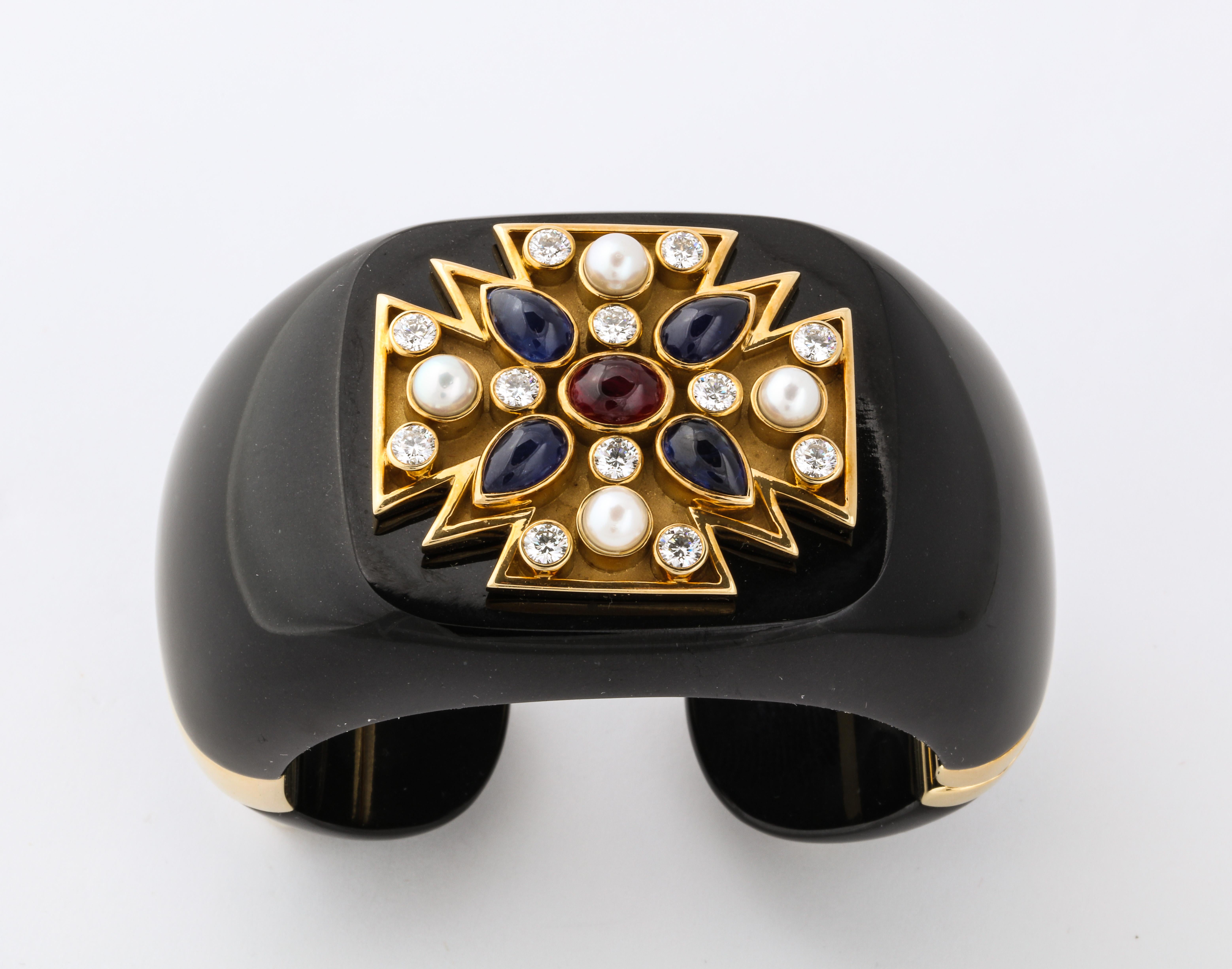 Originally designed for Coco Chanel in the 1930's, the maltese cross cuff remains one of Verdura's most truly iconic designs.  The bold cuff is carved from black jade and the maltese cross is set with pearls, diamonds, sapphires and a central ruby. 