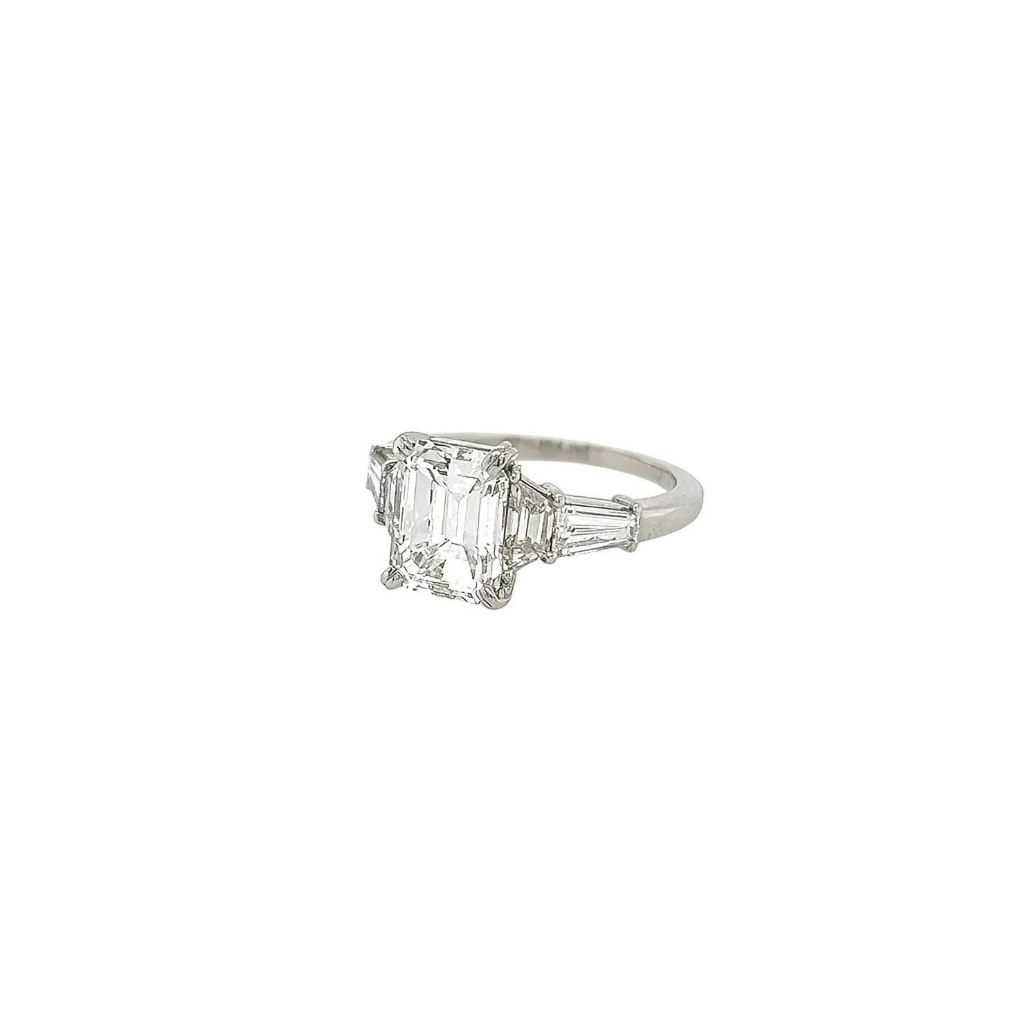 A platinum and diamond ring.  Verdura,   Centering an emerald cut diamond weighing 2.43 carats, mounted in platinum, flanked by a pair of trapezoid cut diamonds totaling .52 carat and a pair of tapered baguette diamonds totaling .46 carat.  Size